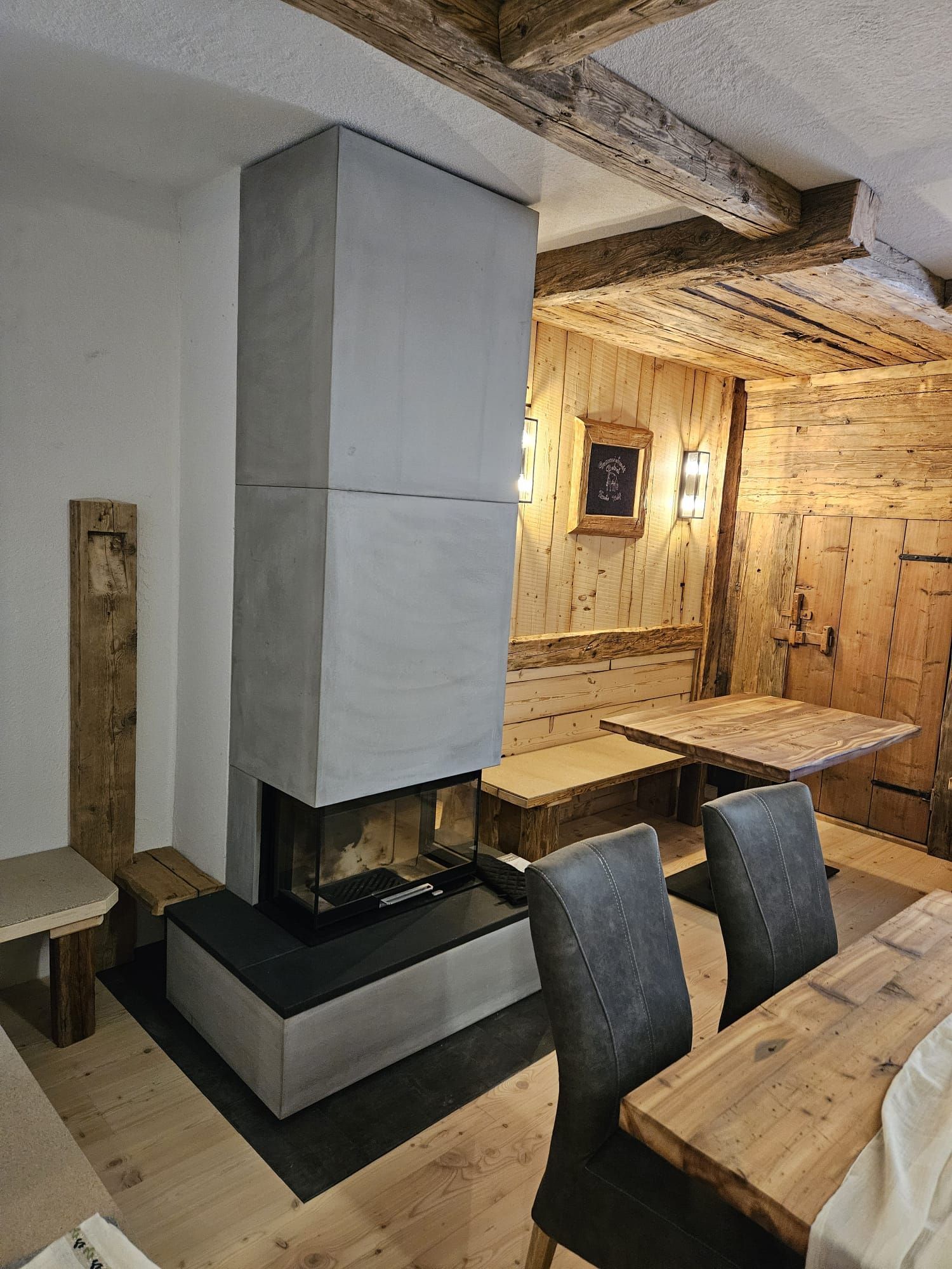 Rustikales Esszimmer mit weißem Kamin, Holztischen und dunklen Stühlen