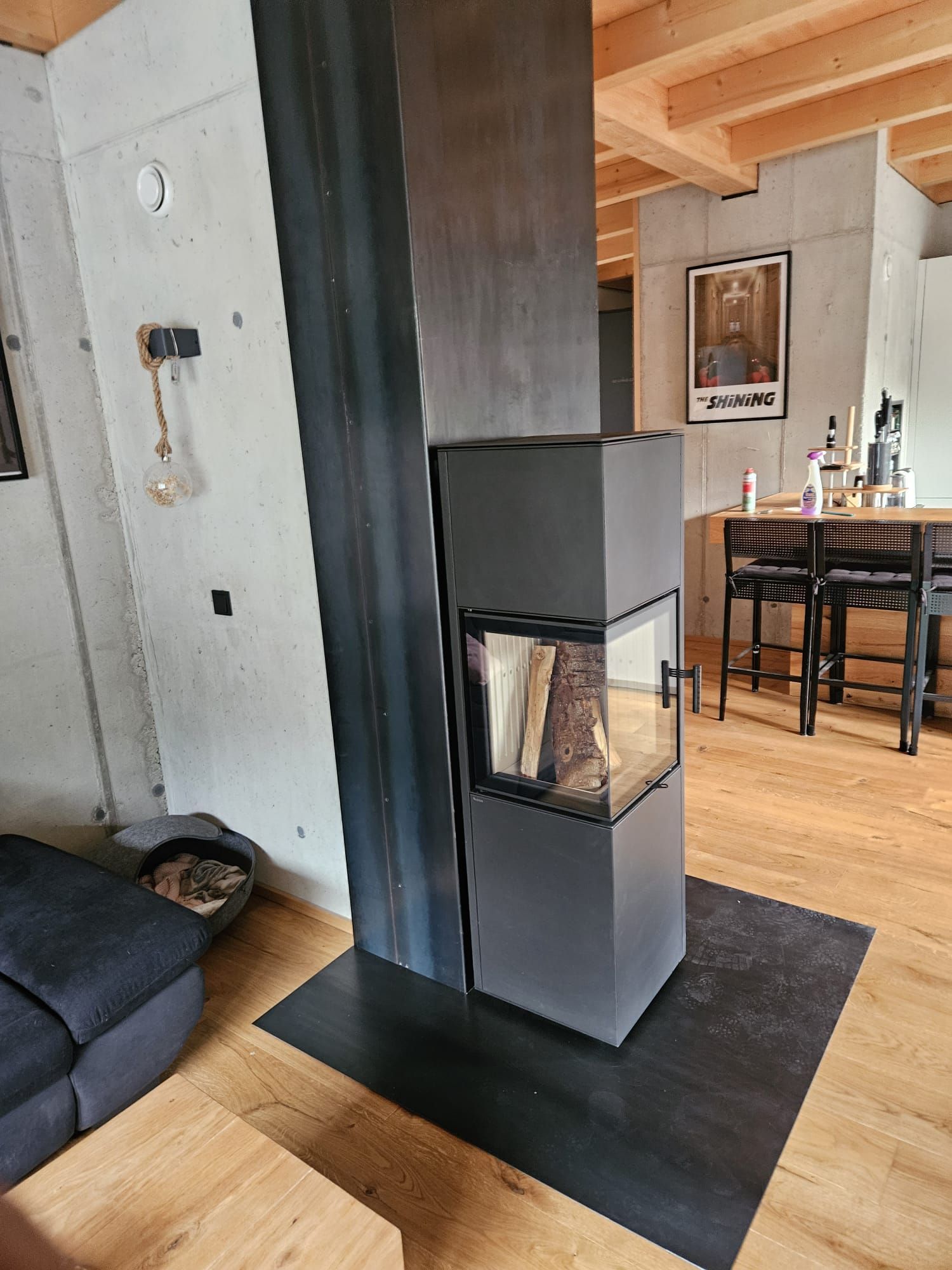 Modernes Wohnzimmer mit schwarzer Kaminsäule, grauen Wänden und Holzboden