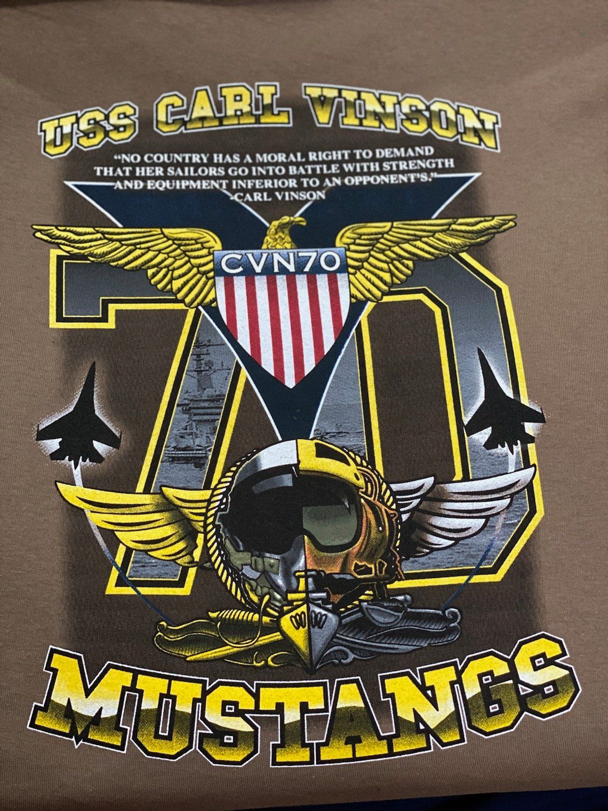 Graphic T-shirt design with gold wings, skull emblem, and large “70” for “Mustangs” team anniversary