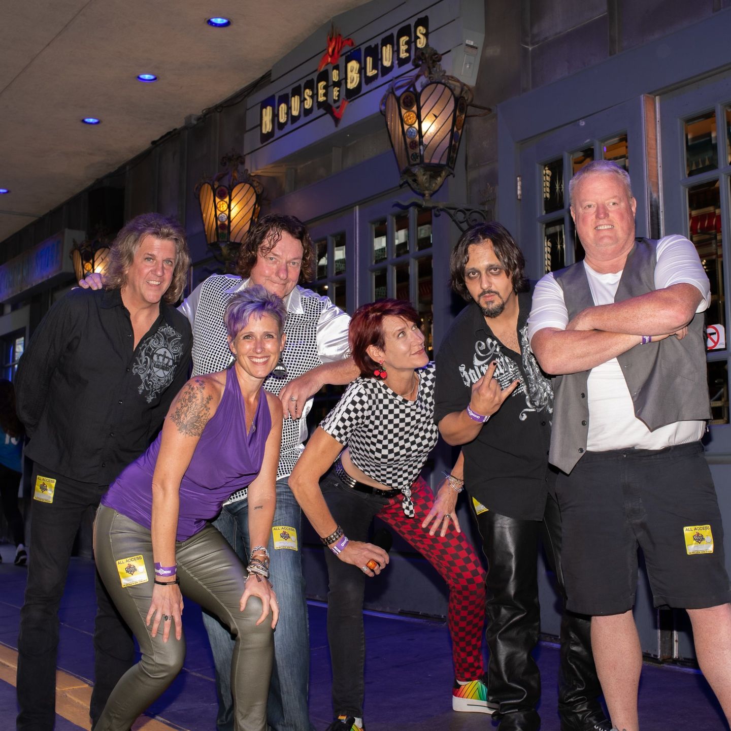 A group of people posing for a picture in front of a building that has the word blues on it