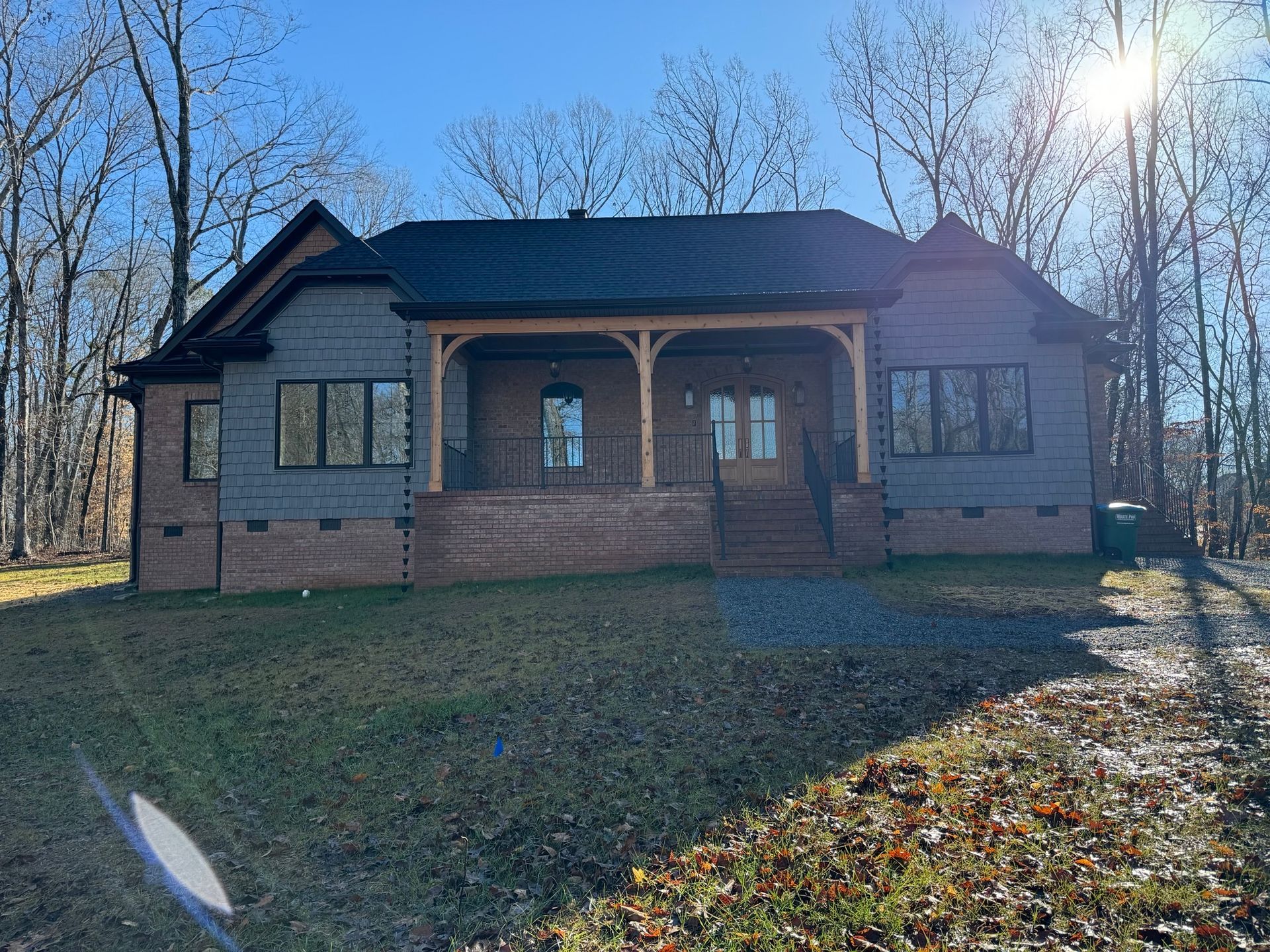A large house with a porch and a lot of windows is surrounded by trees.