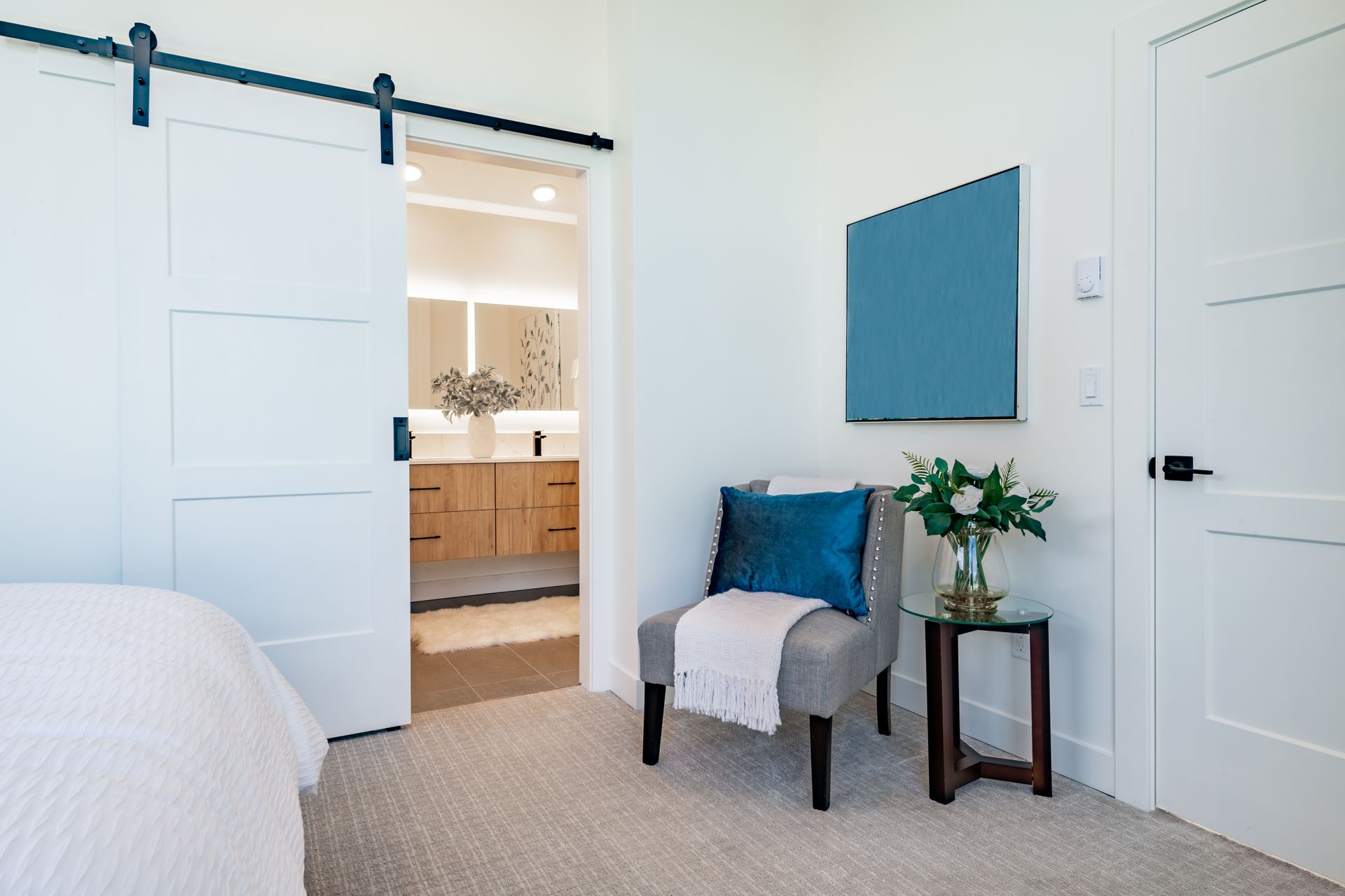 A bedroom with a chair and a television on the wall.