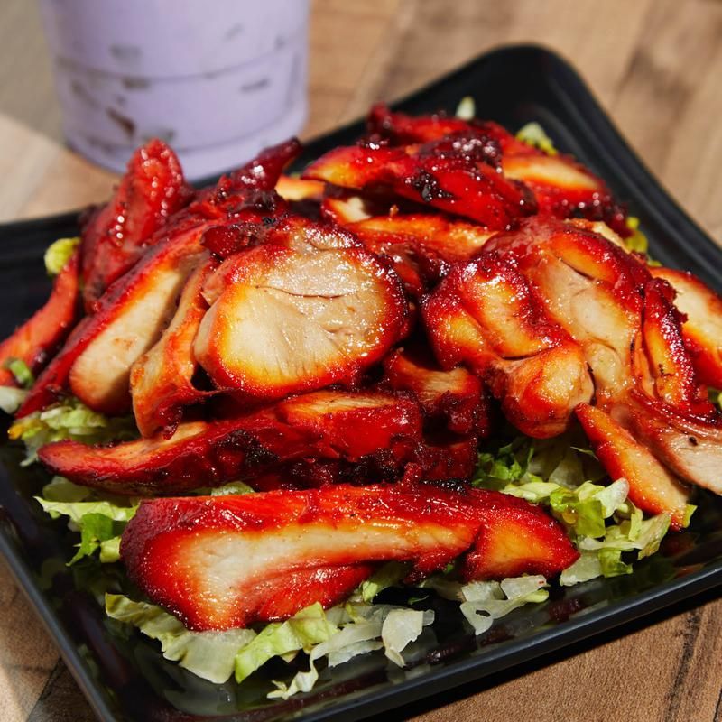 Spicy sliced grilled meat on a black plate with shredded lettuce garnish