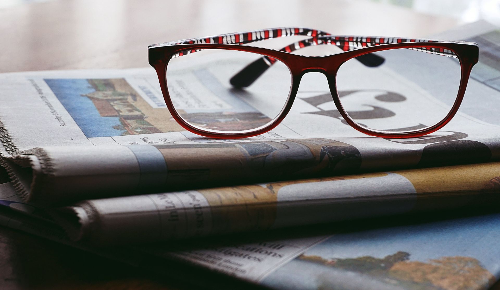 Leesbril op een opengeslagen krant, symbool voor een rustig moment thuis.