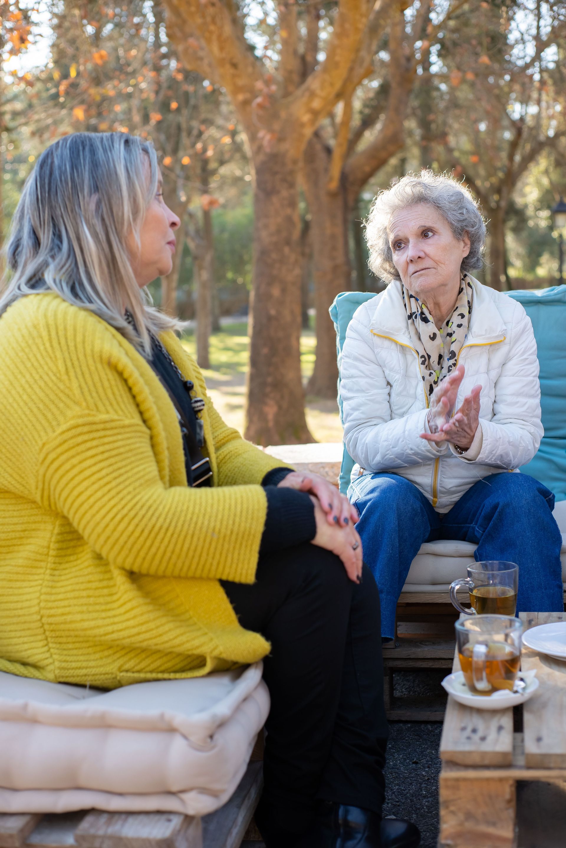 Twee vriendinnen hebben een warm gesprek samen buiten in de tuin.