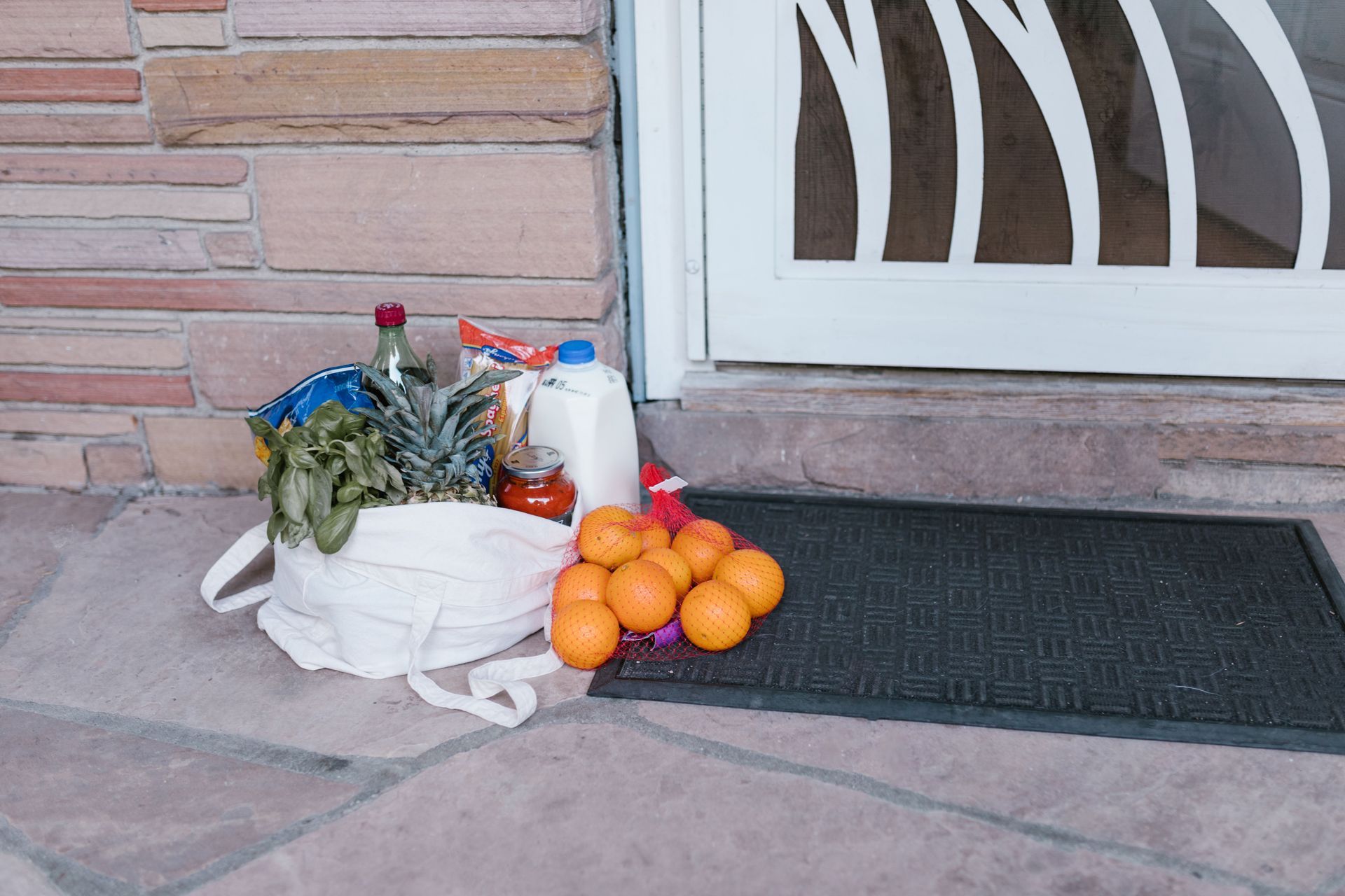 Boodschappentas met verse groenten en fruit, klaargezet bij de voordeur.