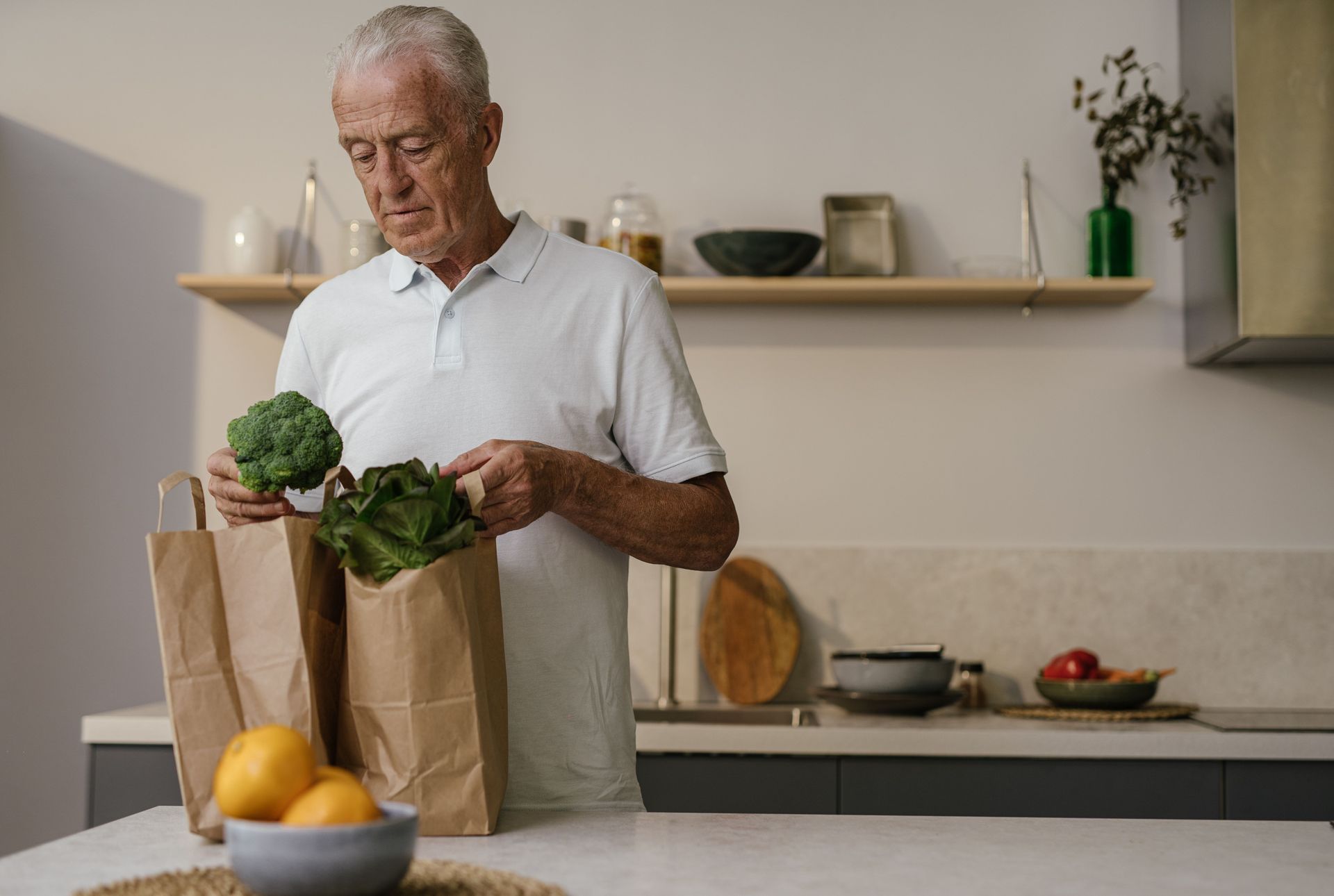 Een oudere man pakt zelf de verse boodschappen uit in zijn keuken.