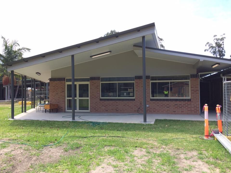 A Large Brick Building With A Covered Porch And A Lot Of Windows — Nambucca Construction In Nambucca Heads, NSW