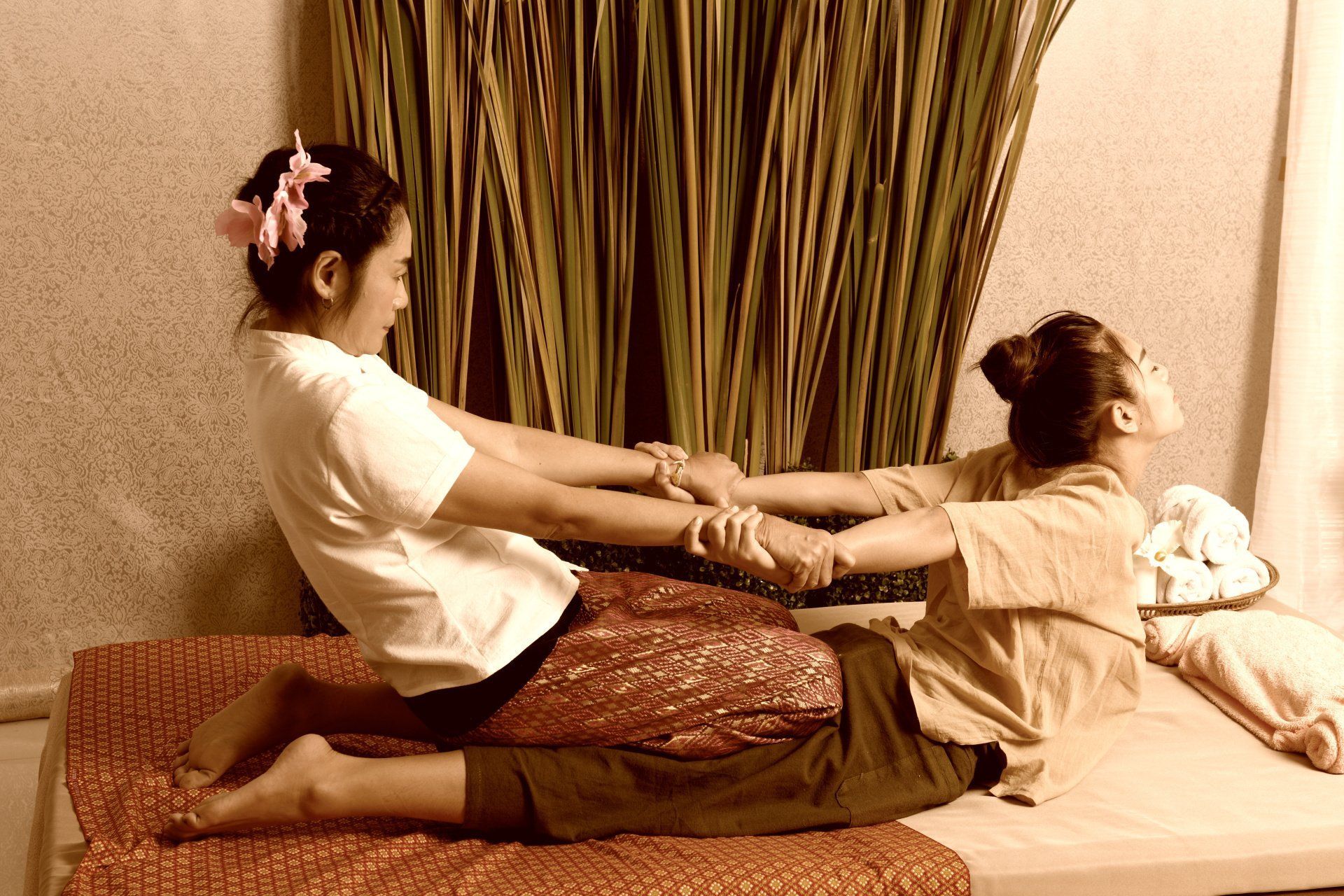 two women are laying on a bed getting a body massage.