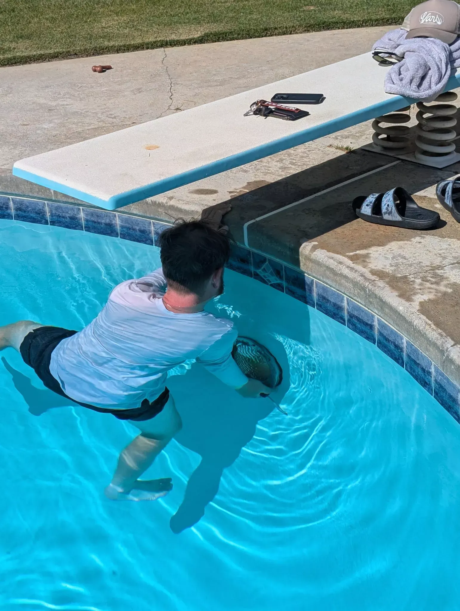 Hurst Pool Service technician in the water making a repair under a pool diving board in Bakersfield