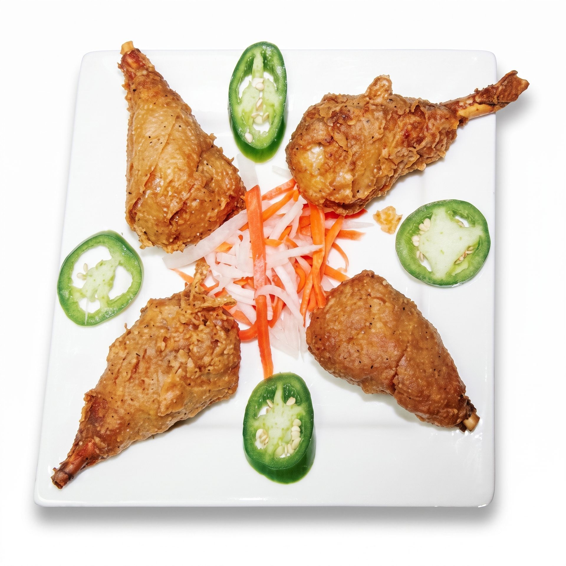 Plate of fried chicken pieces garnished with jalapeño slices and shredded carrots on a white dish