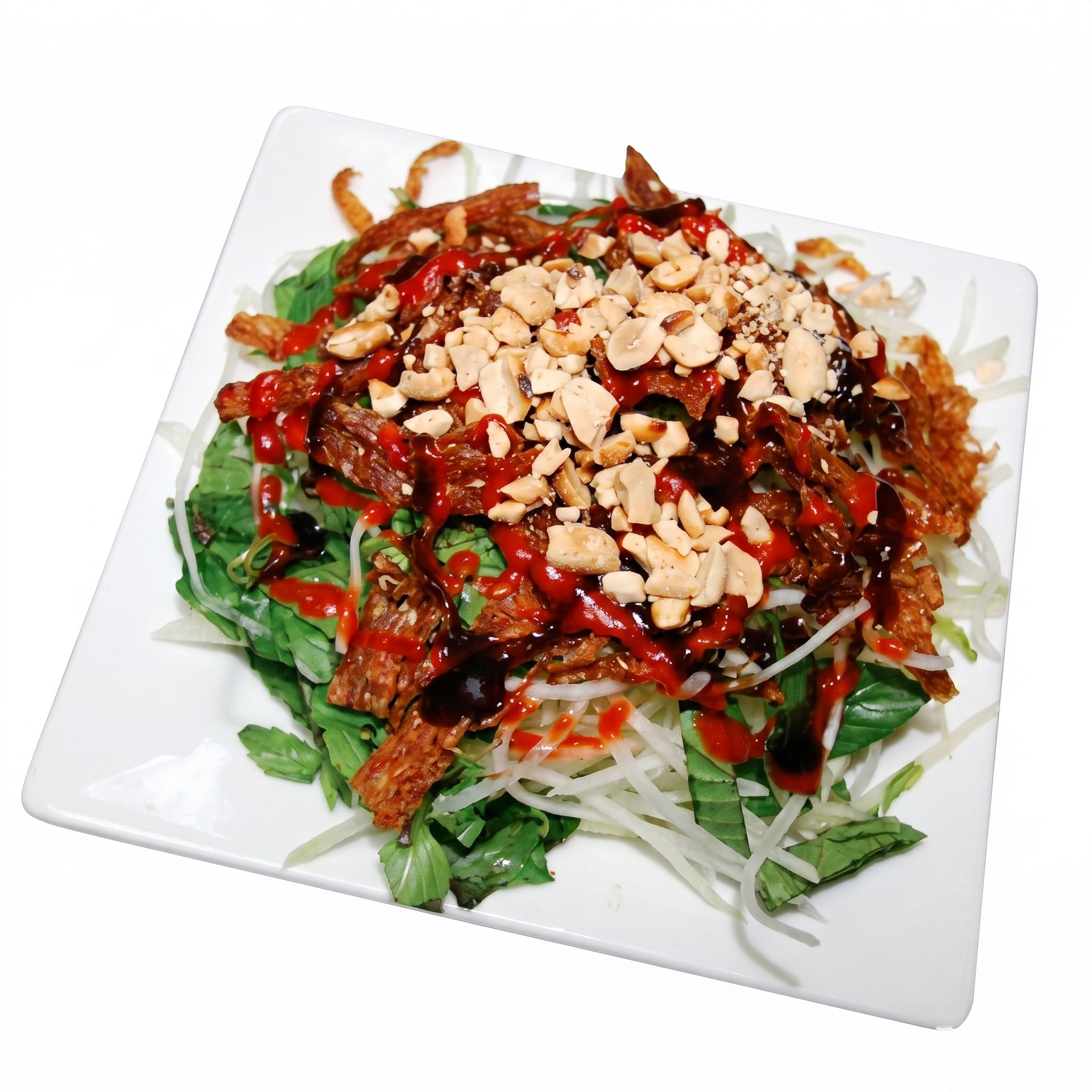 Spicy noodle salad topped with peanuts and red chili sauce on a white plate