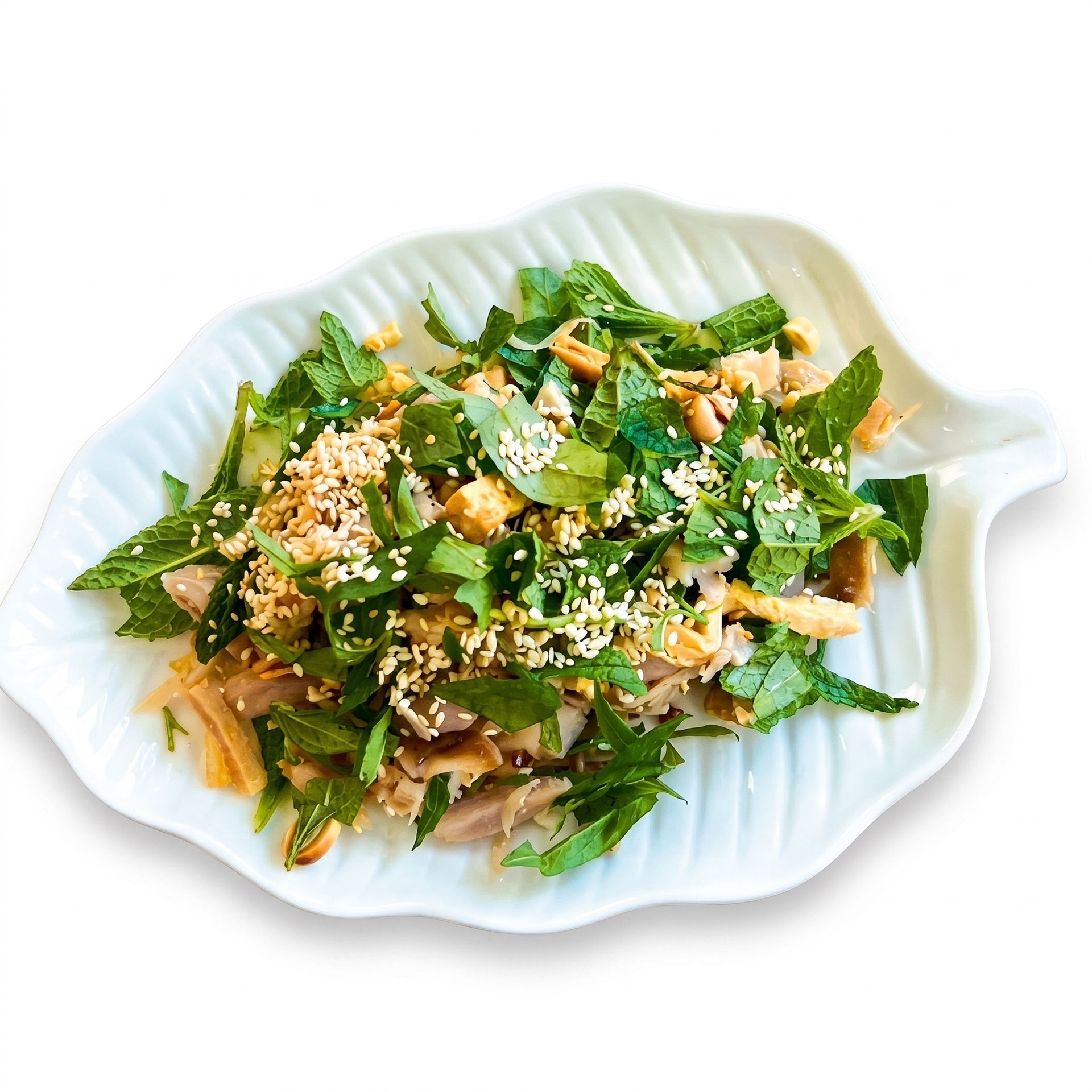 Plated leafy green salad topped with sesame seeds on a white dish