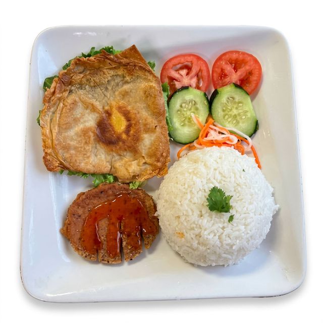 Japanese bento with grilled fish, rice ball, sliced tomatoes and cucumbers on a white plate