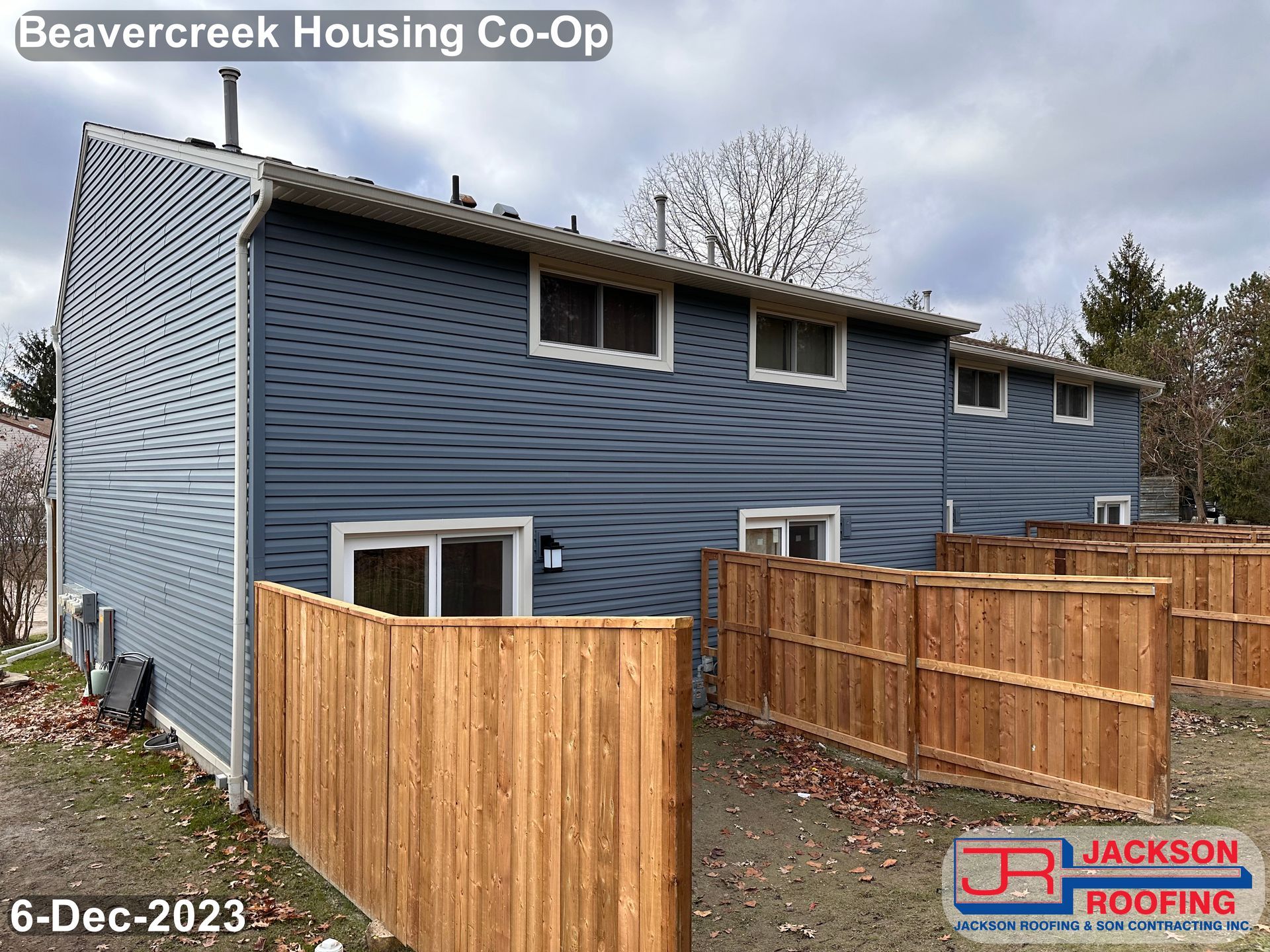 A blue house with a wooden fence in front of it.