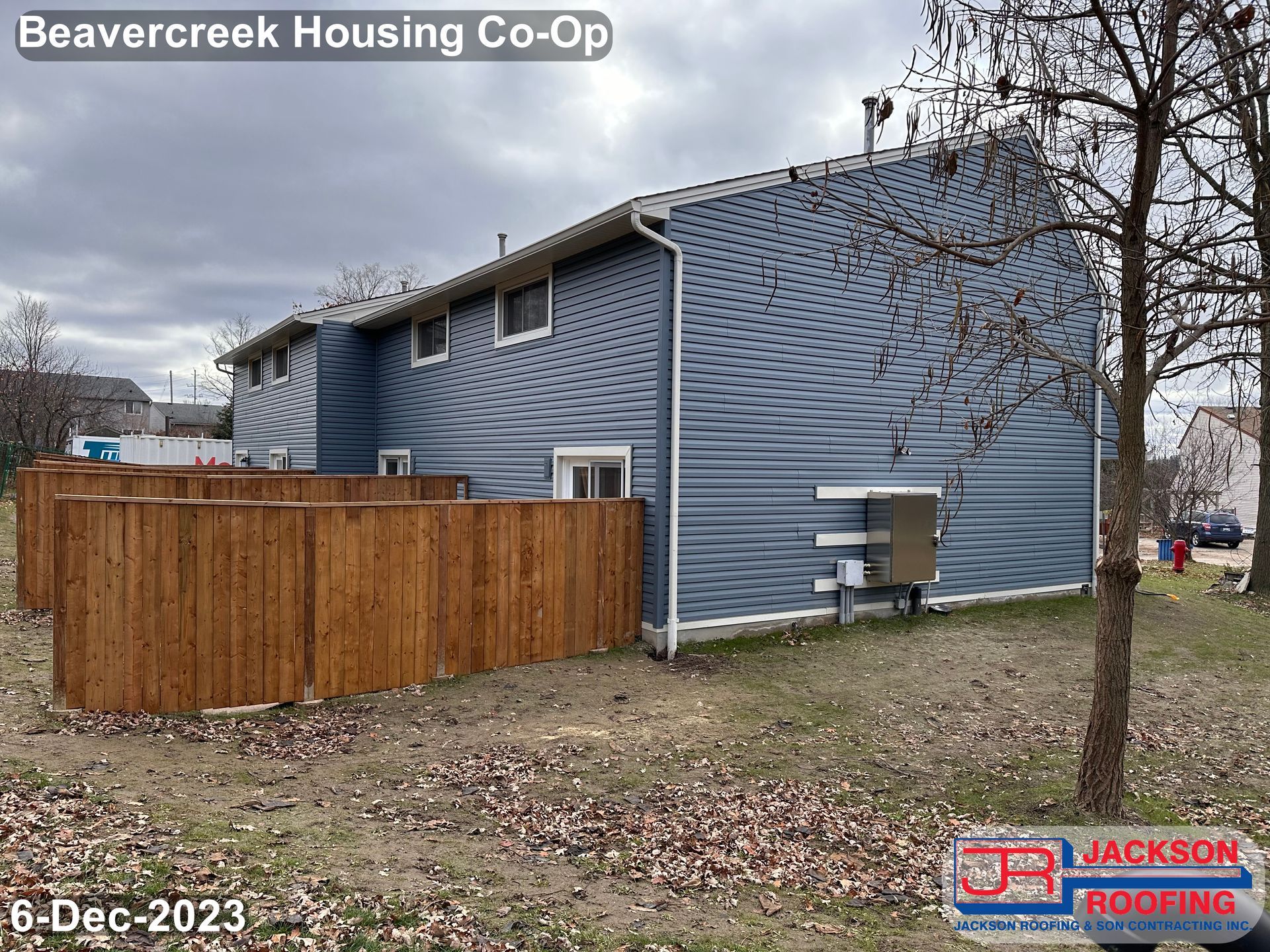 A blue house with a wooden fence in front of it.