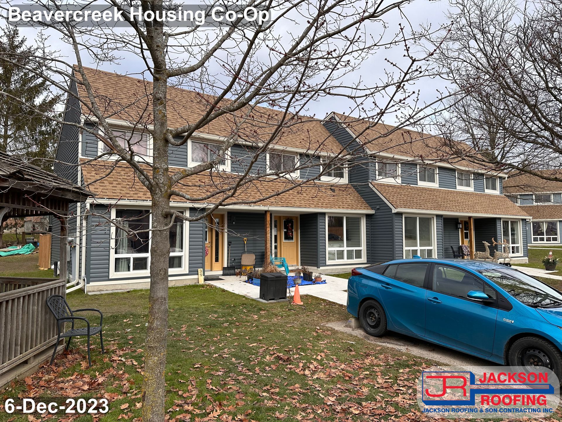 A blue car is parked in front of a row of houses.