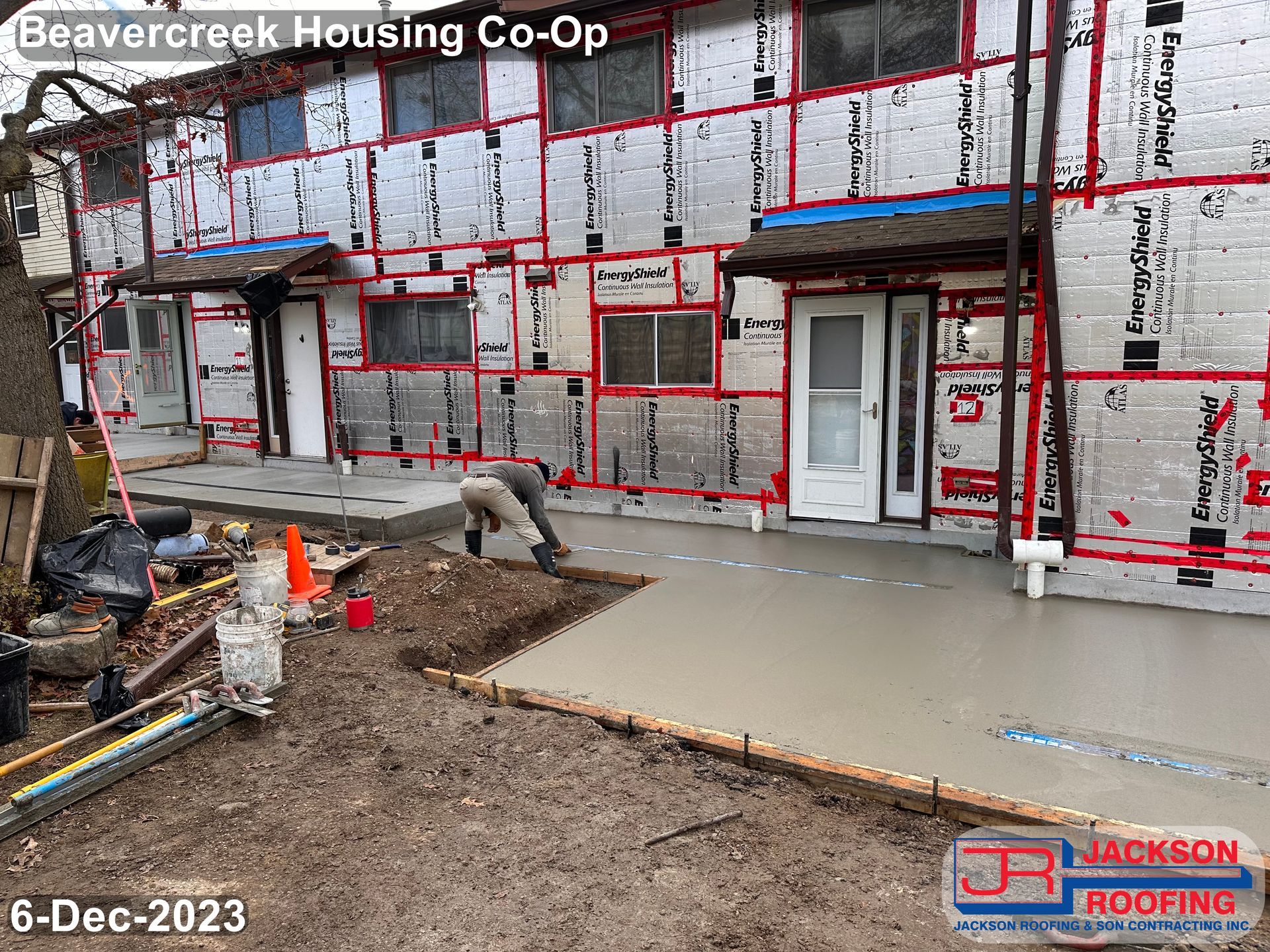 A man is working on the sidewalk in front of a building.