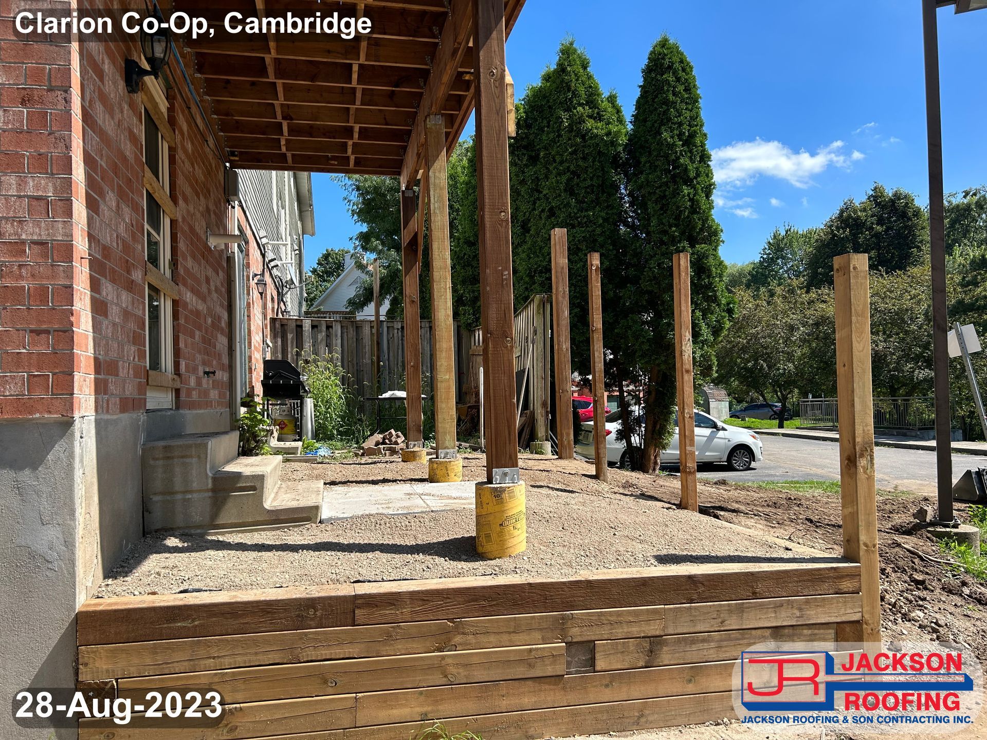 A wooden porch is being built on the side of a brick building.
