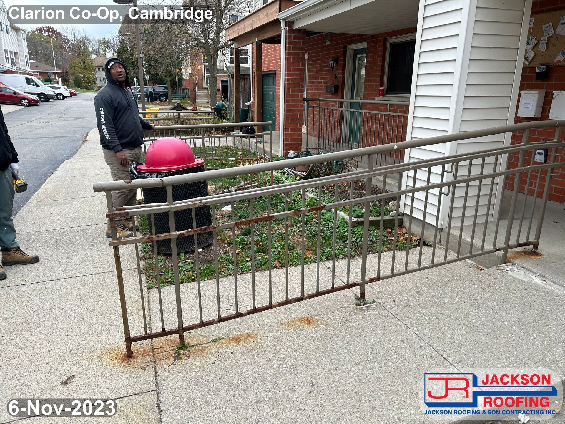A man is standing next to a fence in front of a house.