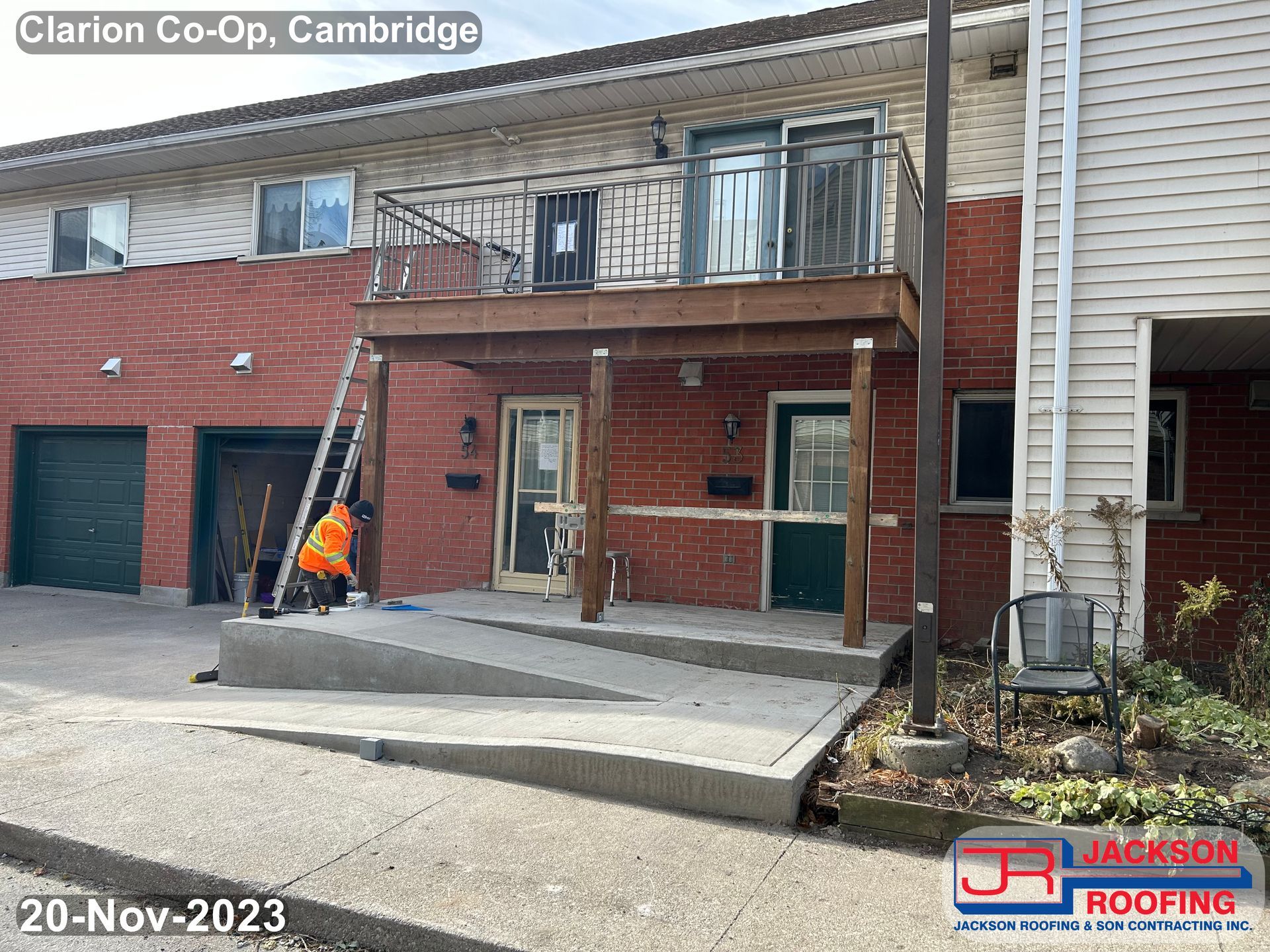 A man is standing on a ramp in front of a house with a balcony.