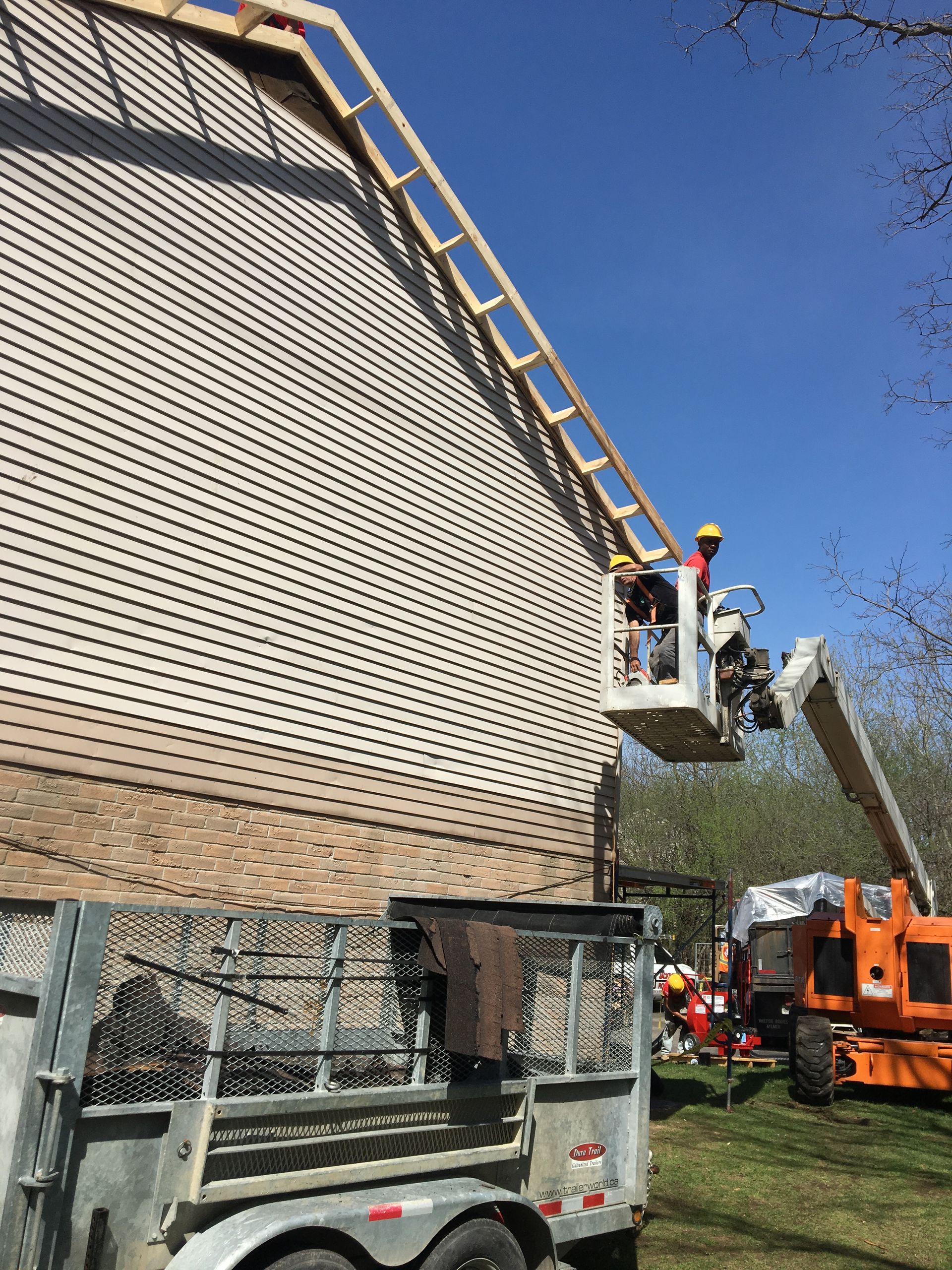 A crane is being used to build a roof on a house.