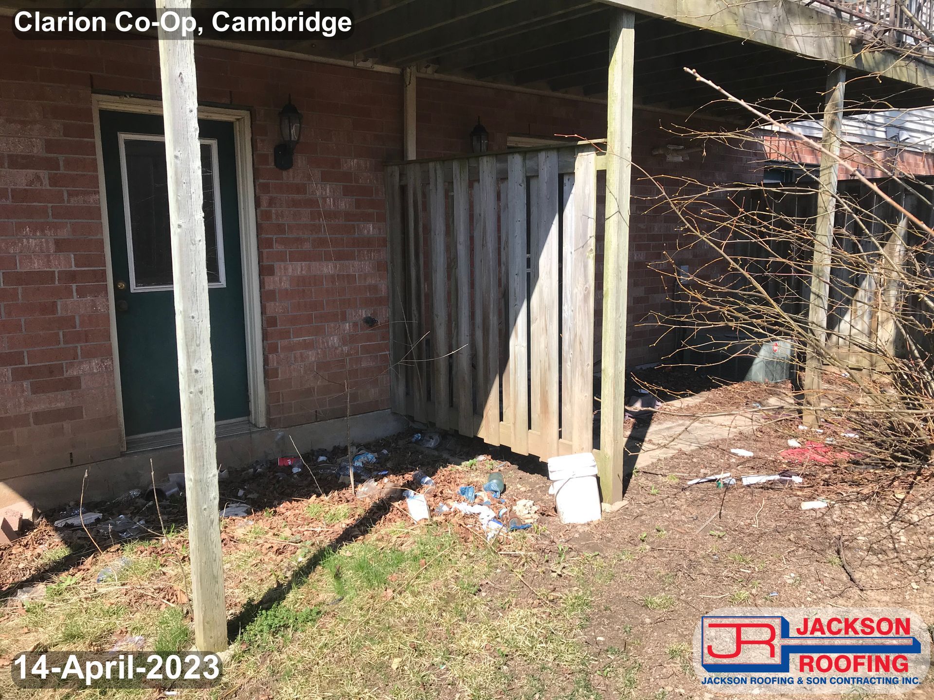 A brick house with a porch and a wooden fence.