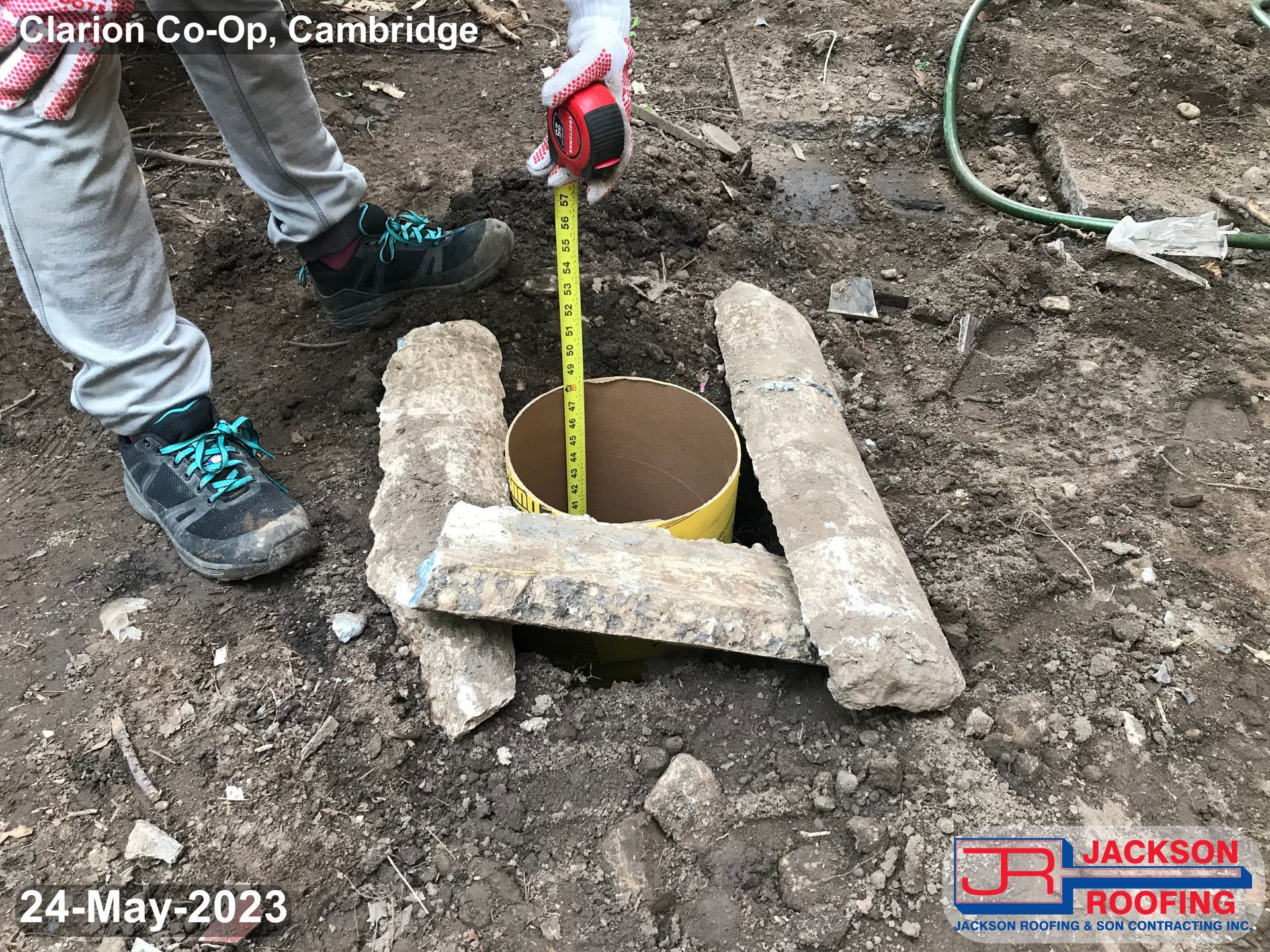 A person is measuring a hole in the ground with a tape measure.