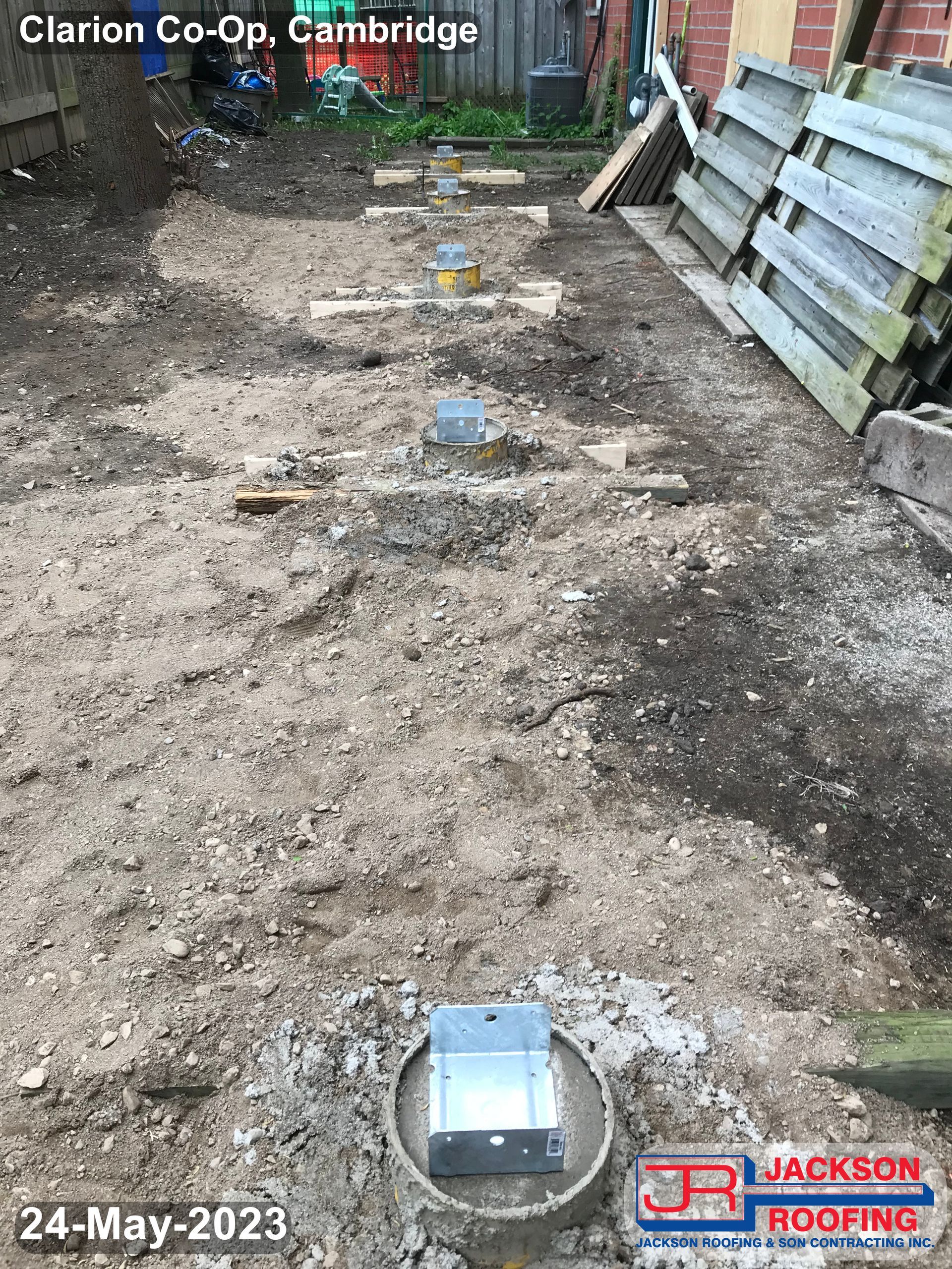 A row of concrete pillars are being built in a backyard.