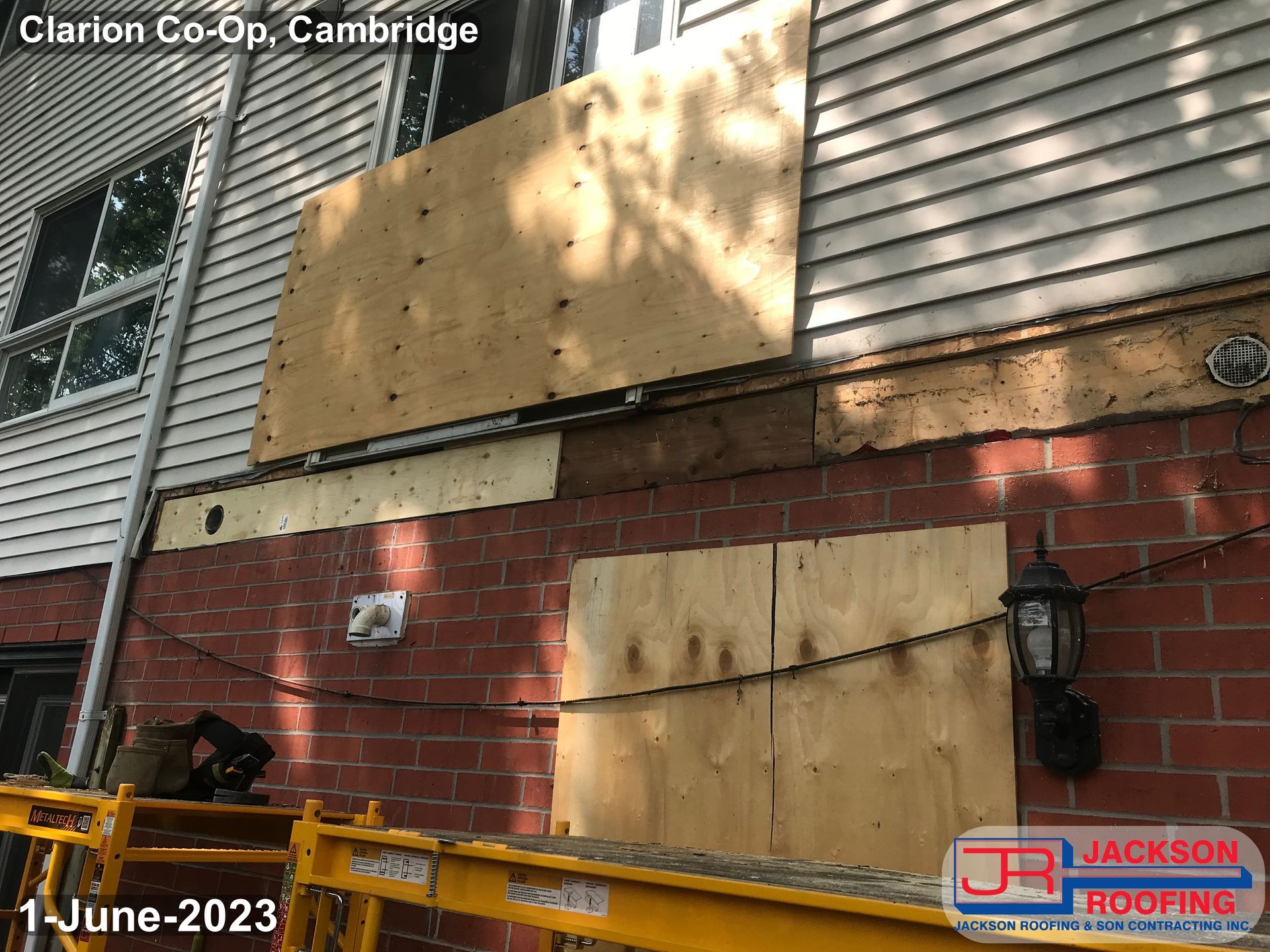 A house with a wooden board on the side of it.