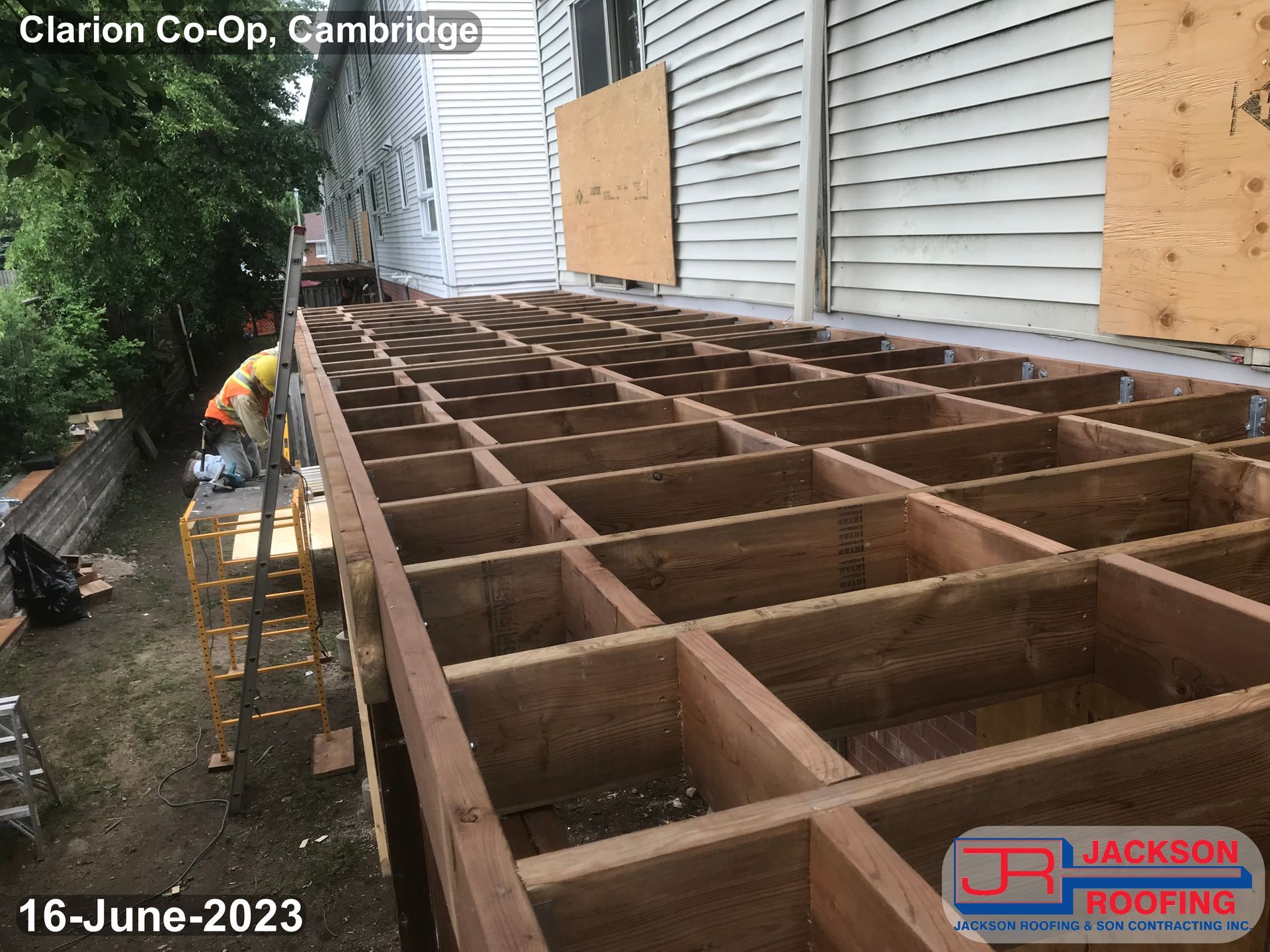 A wooden deck is being built on the side of a house.