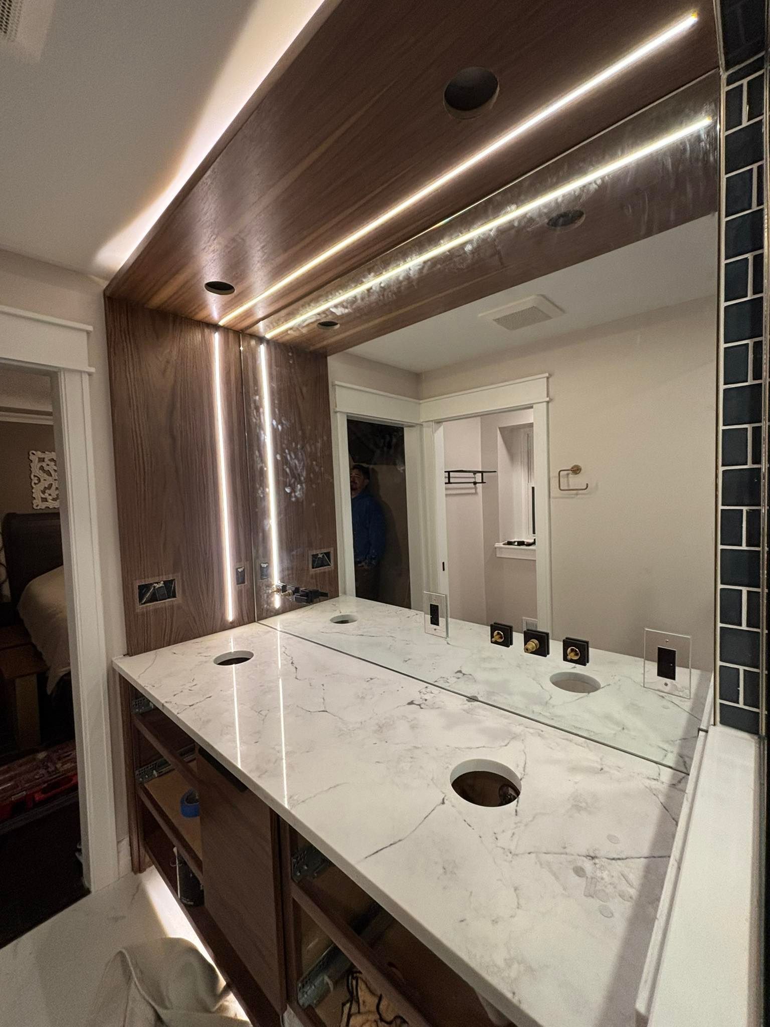 Bathroom vanity with large mirror, marble countertop, and wood-paneled ceiling lighting.