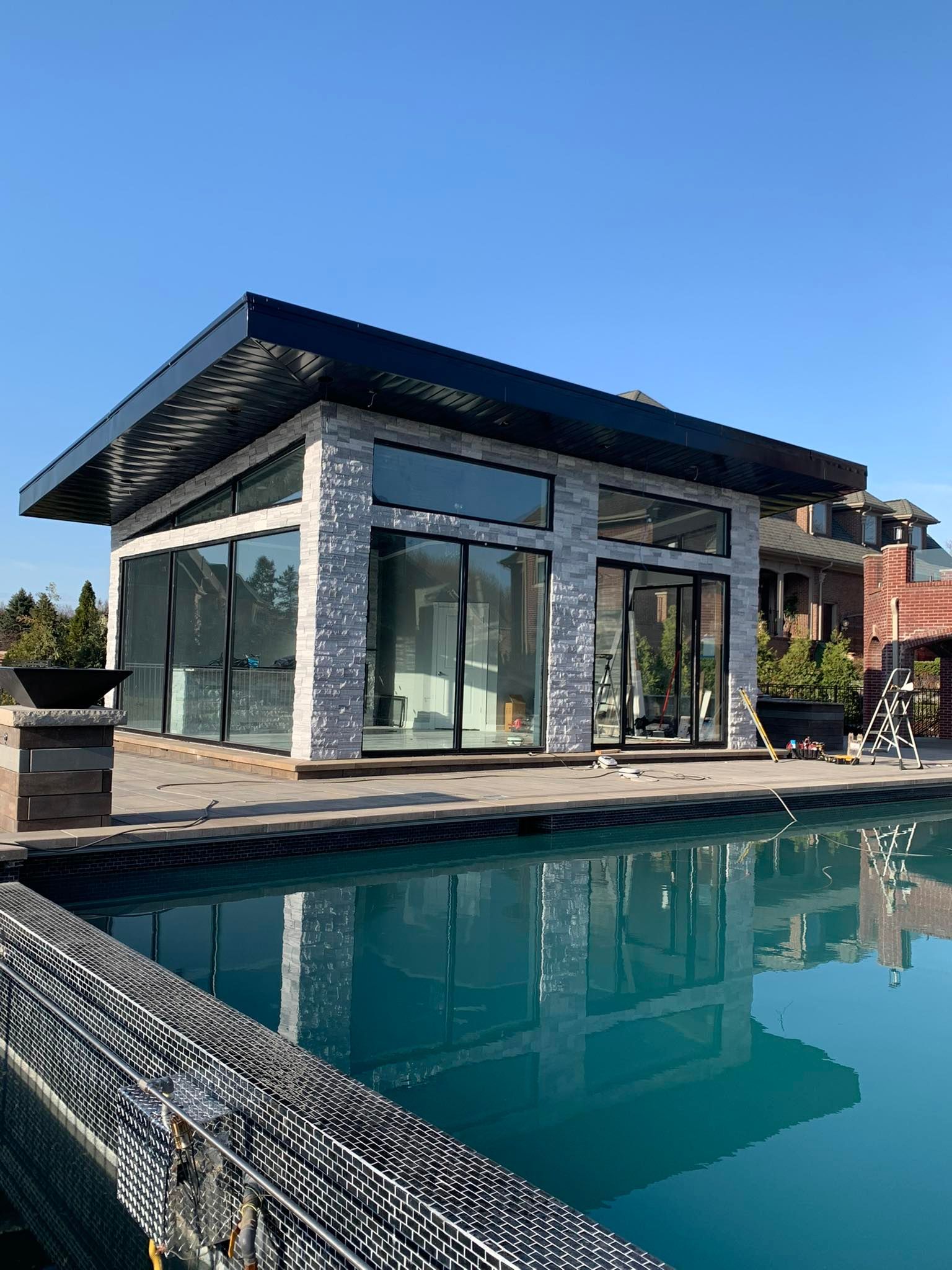 Modern house with large glass windows beside a swimming pool under a blue sky
