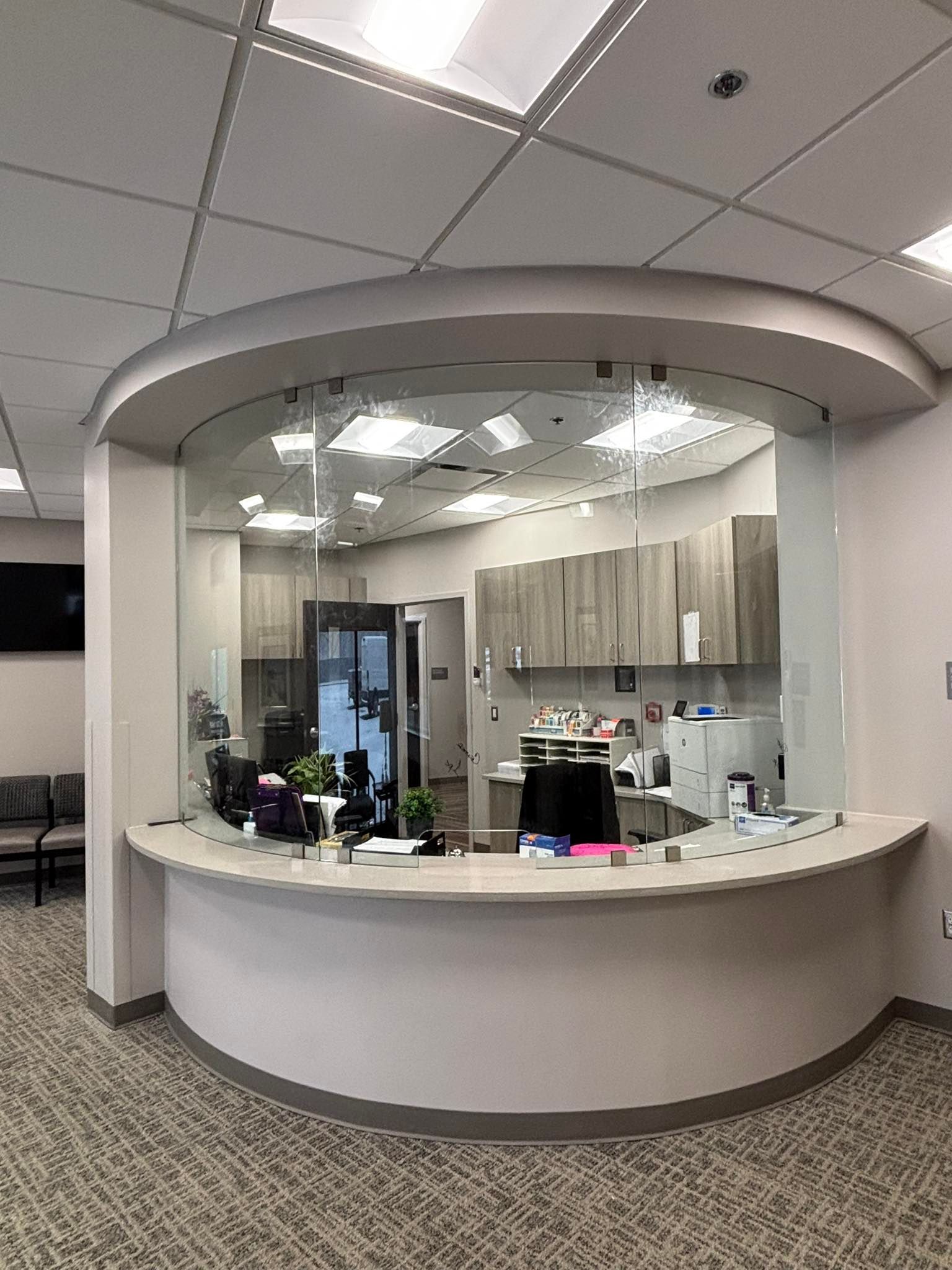Circular front desk in a bright office lobby with beige counters and cabinets.