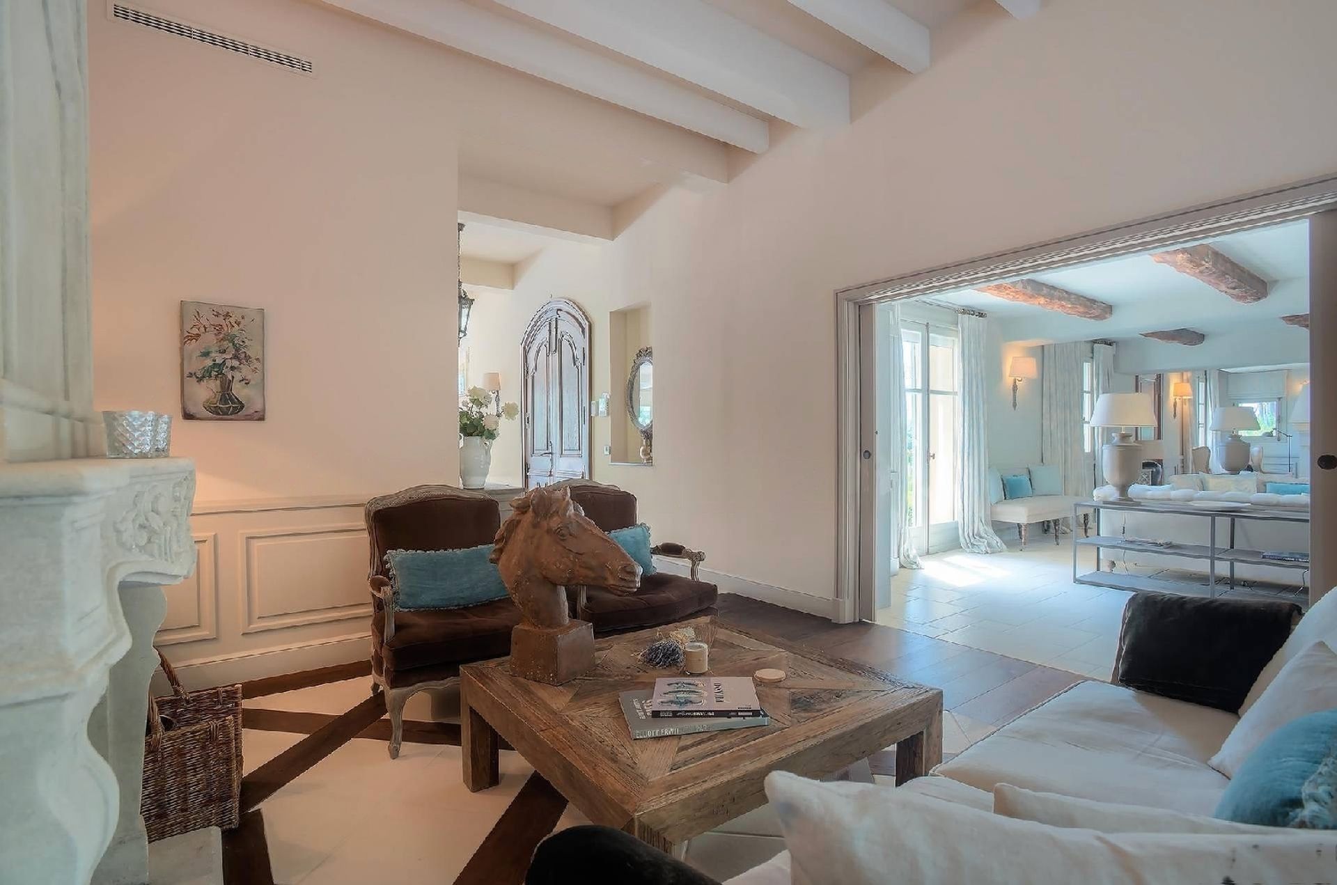 Salon avec murs blancs, parquet et porte cintrée donnant sur un patio ensoleillé.