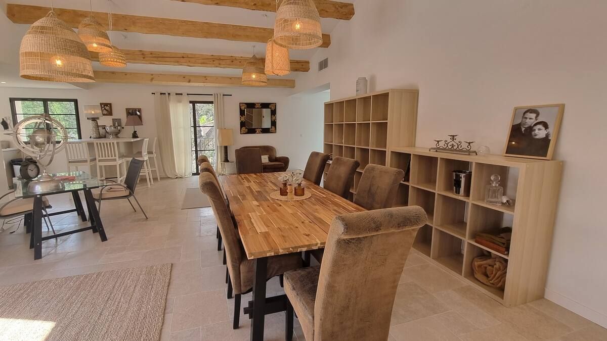 Salle à manger spacieuse avec une longue table en bois, des chaises, une étagère et un éclairage décoratif.