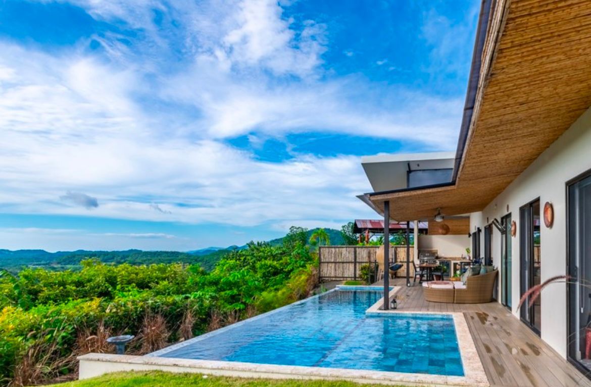 Piscine à débordement donnant sur un paysage verdoyant luxuriant et un ciel d'un bleu éclatant.