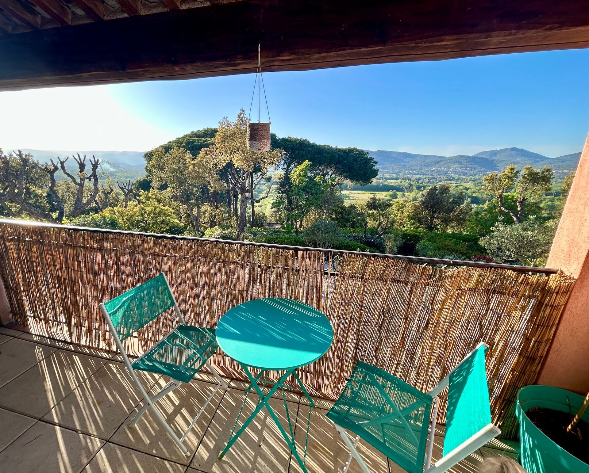 Balcon avec chaises vertes et table donnant sur une vue panoramique.