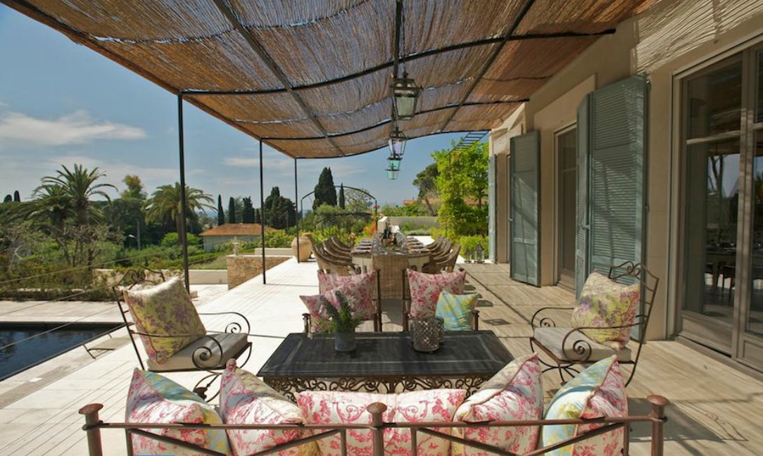 Terrasse avec sièges, table et auvent tissé donnant sur un paysage.