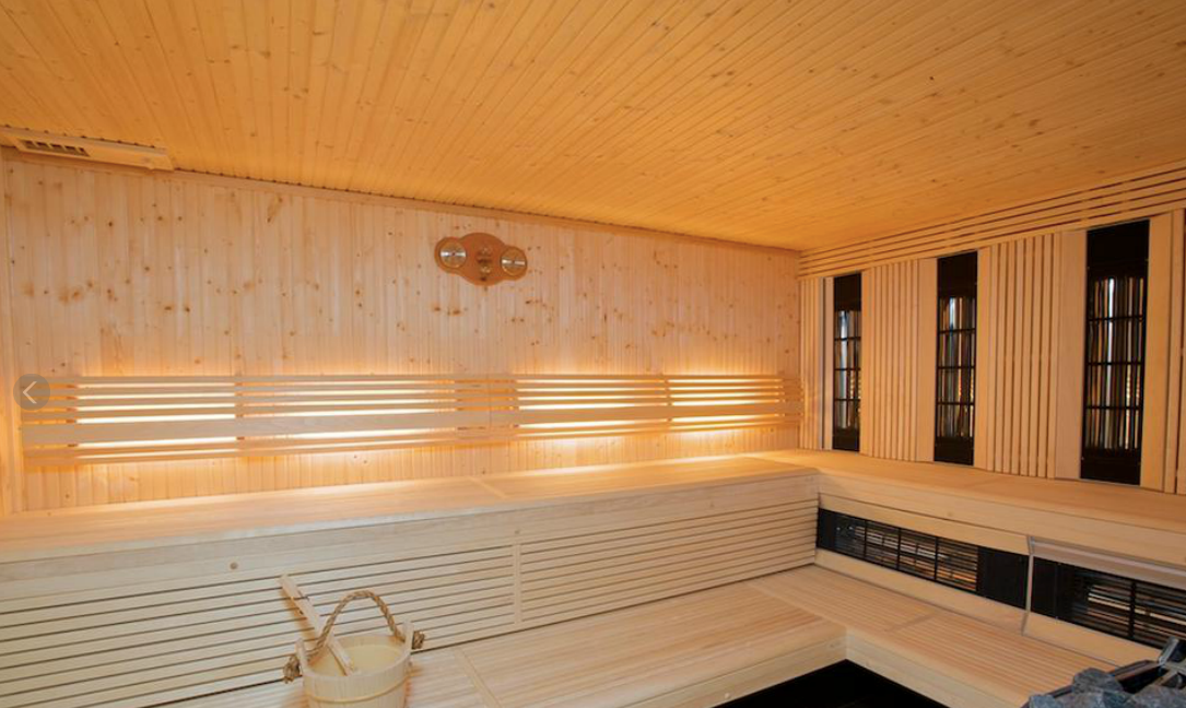 Sauna en bois avec bancs, éclairage et seau.