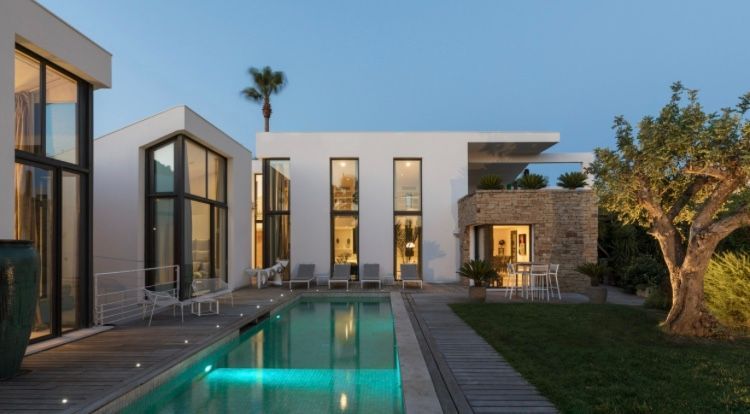 Villa blanche moderne avec piscine et terrasse. Piscine bleue et ciel dégagé.