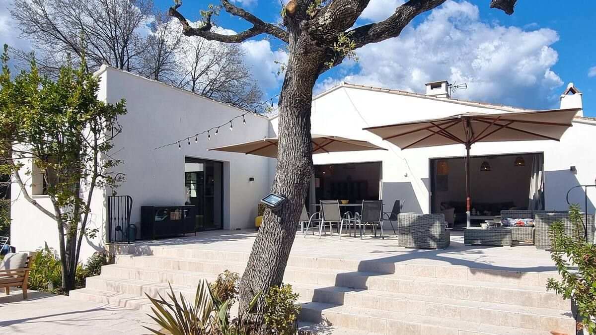Bâtiment blanc avec terrasse et parasols. Ciel nuageux.