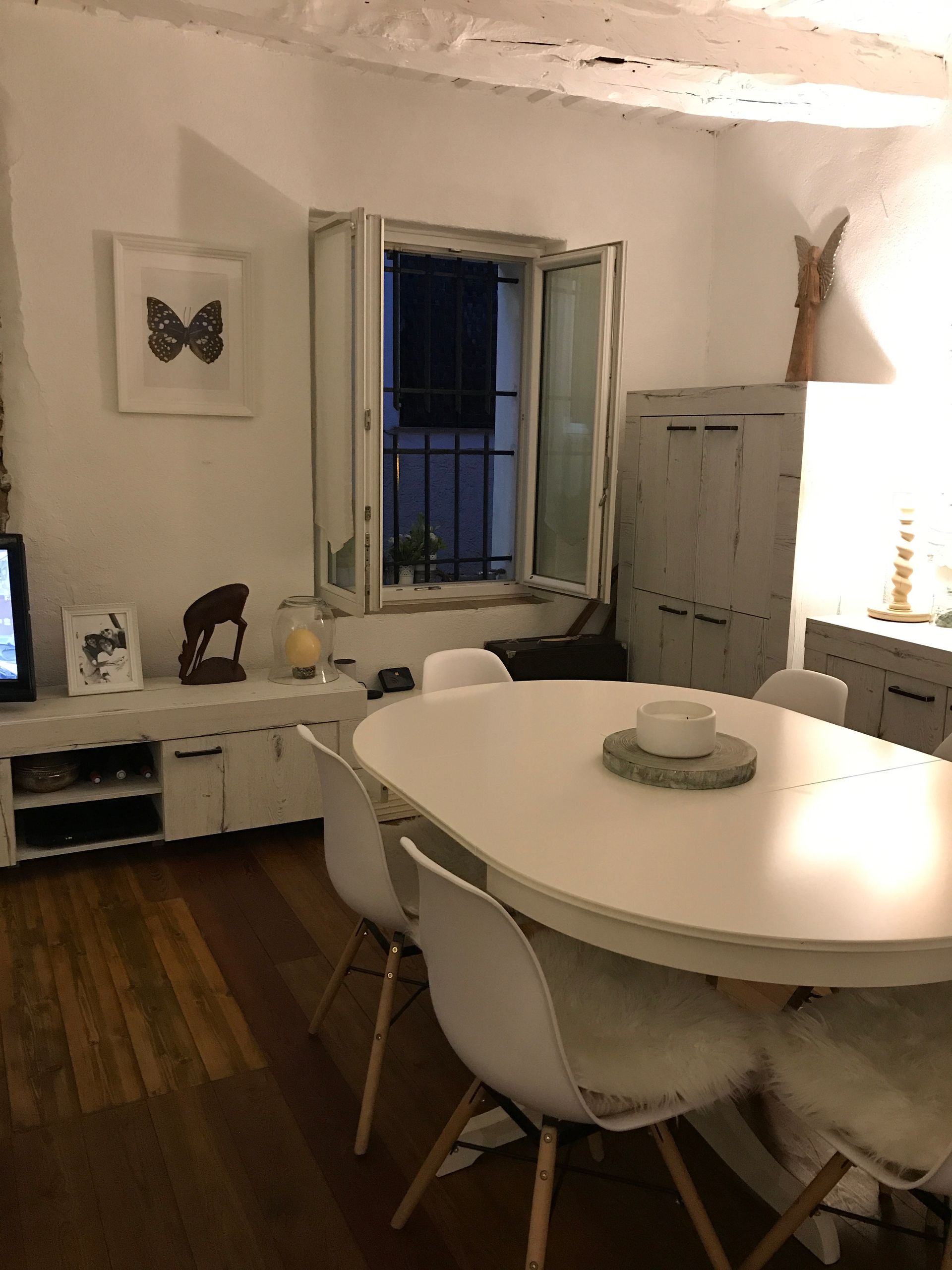 Salle à manger avec table ovale blanche, chaises et fenêtre donnant sur l'extérieur.