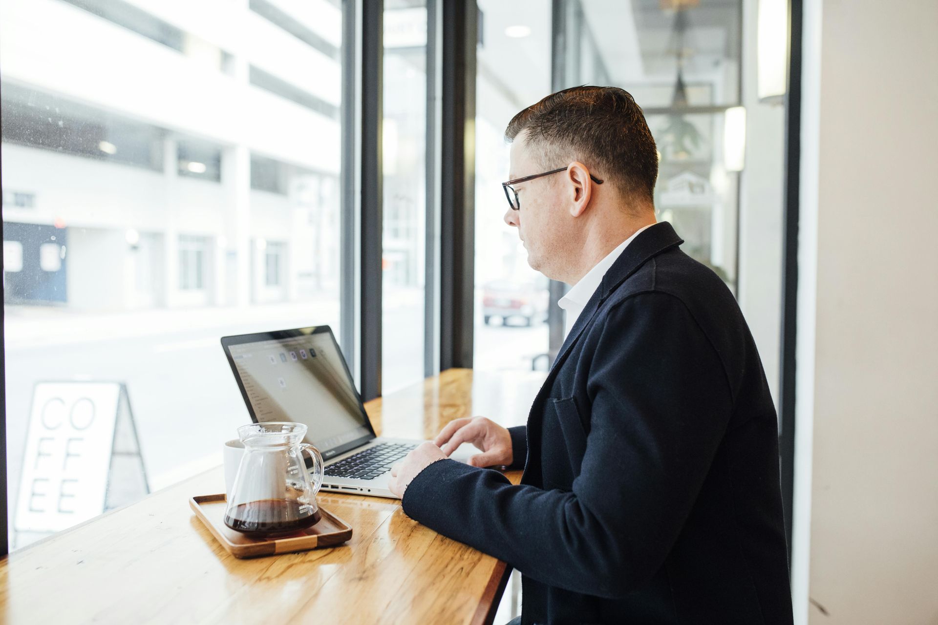 A man in a suit and tie is holding a tablet and giving a thumbs up.