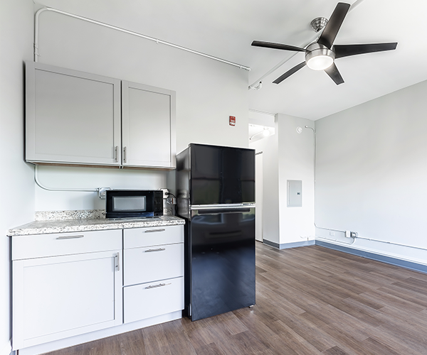A kitchen with a refrigerator , microwave , and ceiling fan