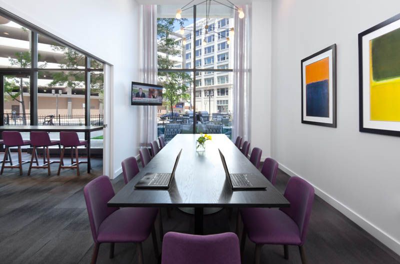 A conference room with a long table and purple chairs