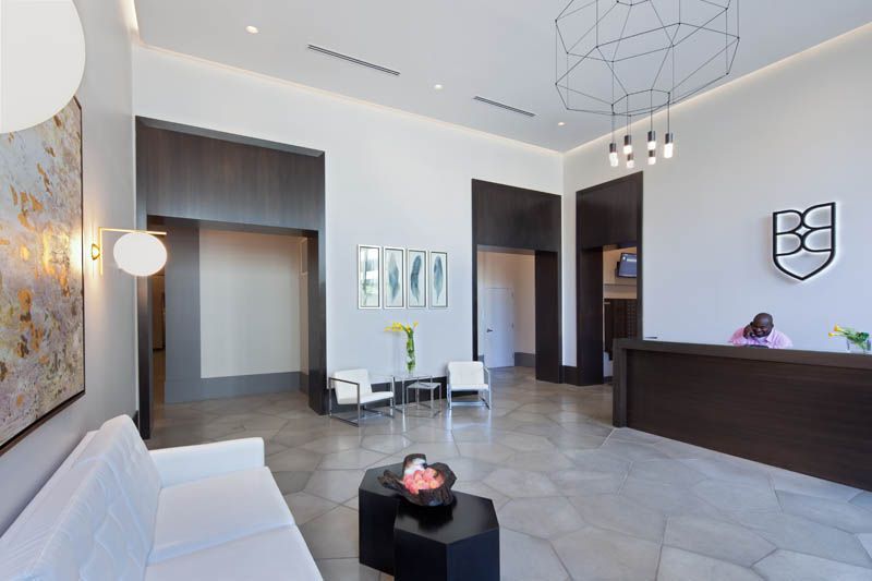 A lobby with a couch , chairs , and a desk.