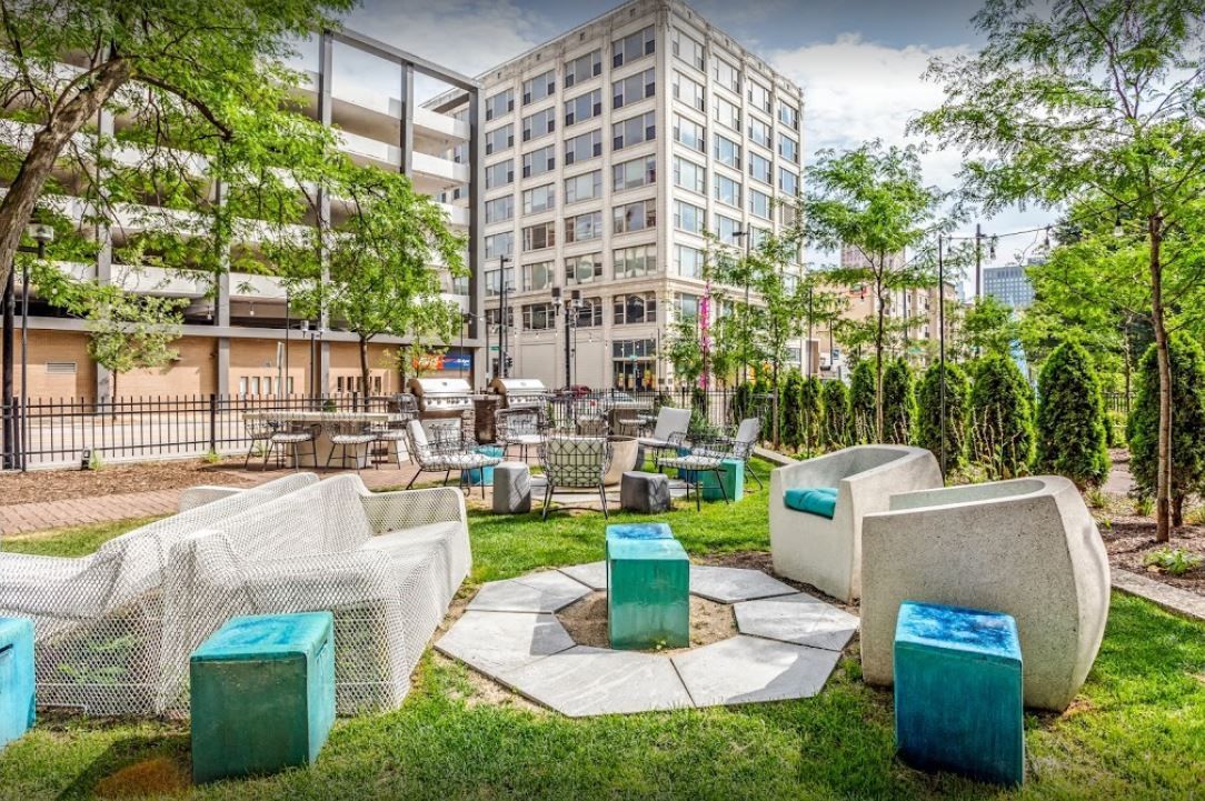 There are a lot of chairs and tables in the grass in front of a building.
