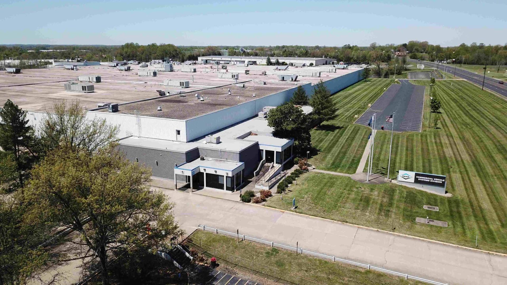 Large industrial building with multiple rooftop units and grassy areas.