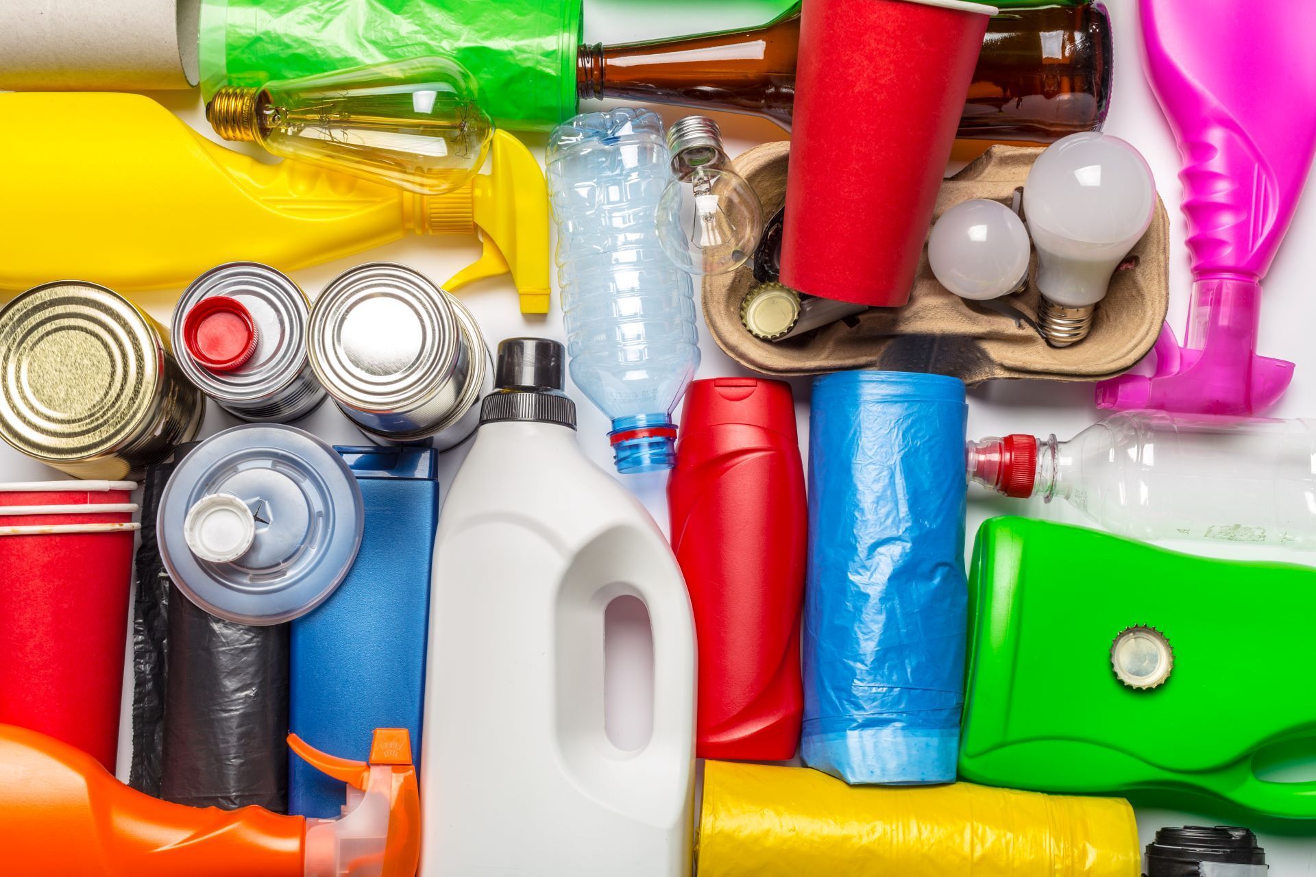 Assorted colorful plastic and metal recyclables sorted in a pile, including bottles, cans, and containers